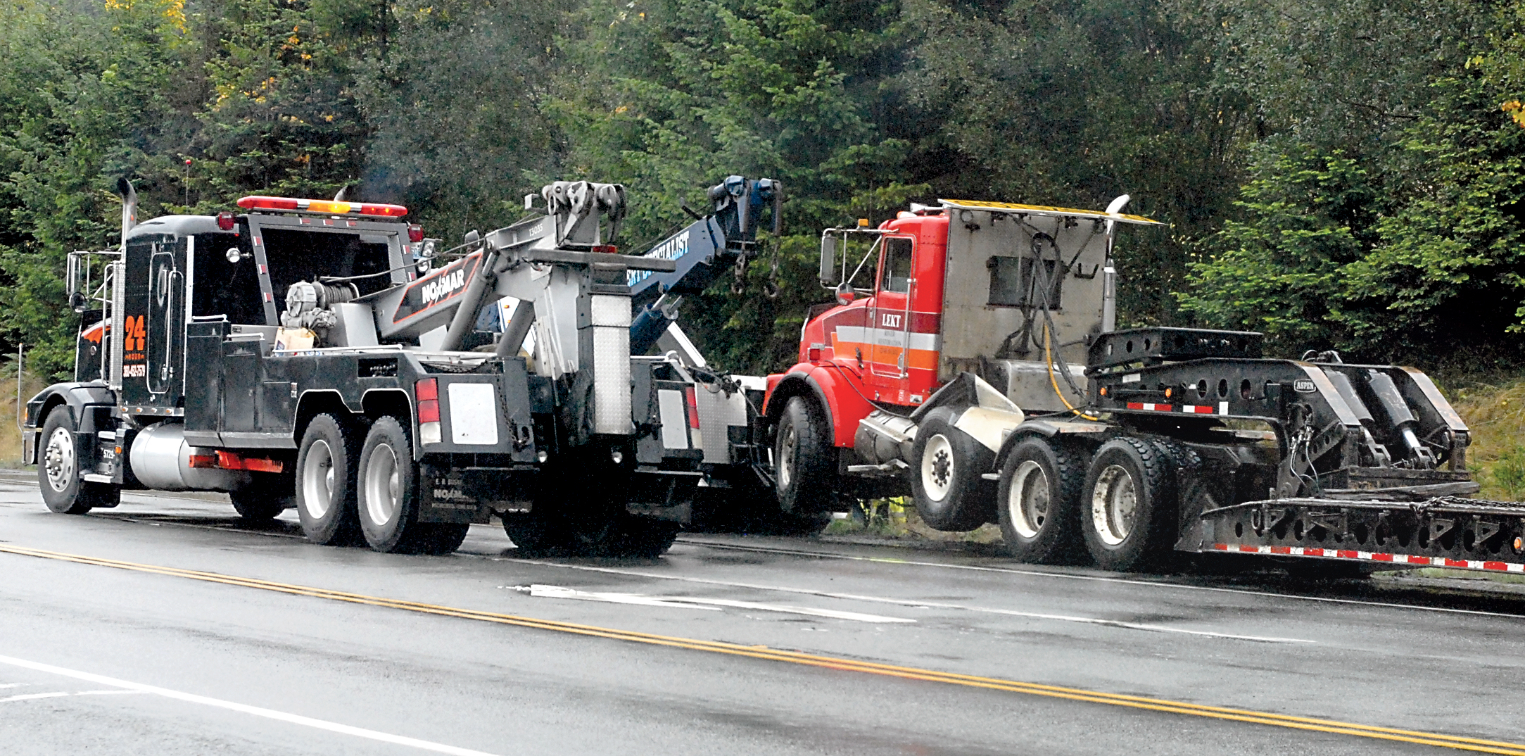 A pair of tow trucks assist with a tractor-trailor that that left the roadway on U.S. Highway 101 near Laird Road west of Port Angeles on Wednesday. Keith Thorpe/Peninsula Daily News