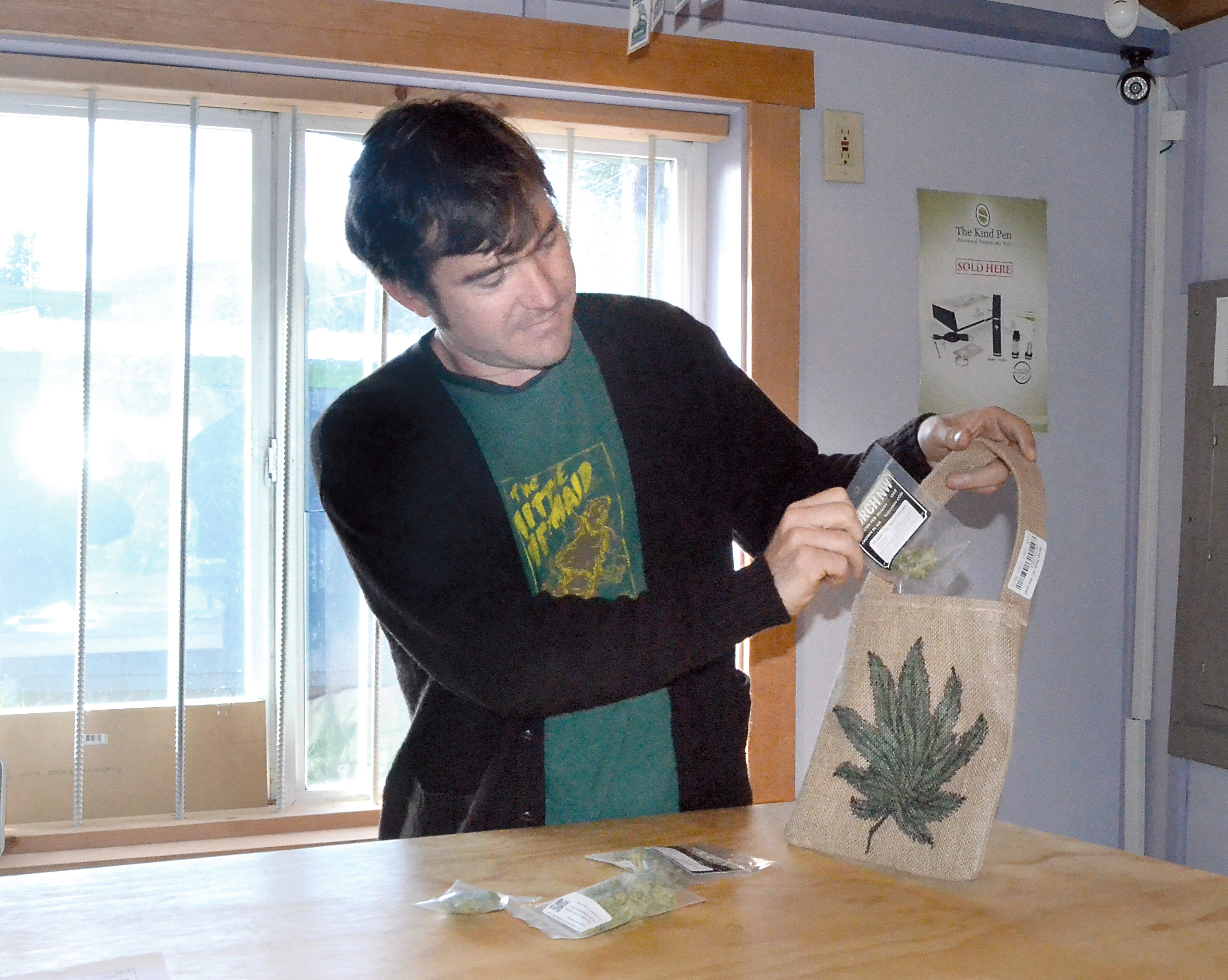 Sea Change Cannabis owner Greg Brotherton shows off some product and a tote bag that will be available in the store beginning Friday