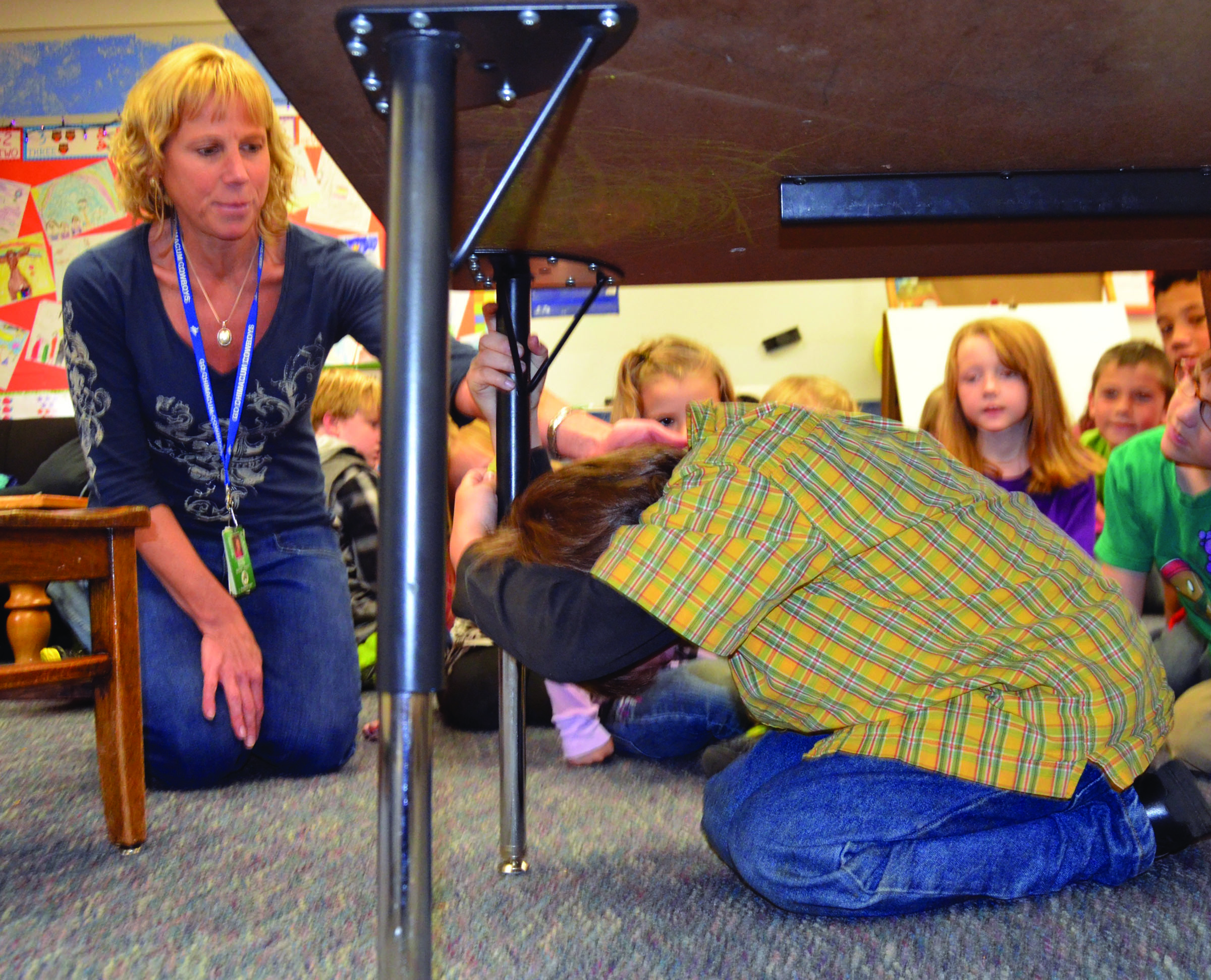 Grant Street Elementary School teacher Sheri Shaw shows first-grader Alex McMahon duck-and-cover in preparation for Thursday's drill. Charlie Bermant/Peninsula Daily News
