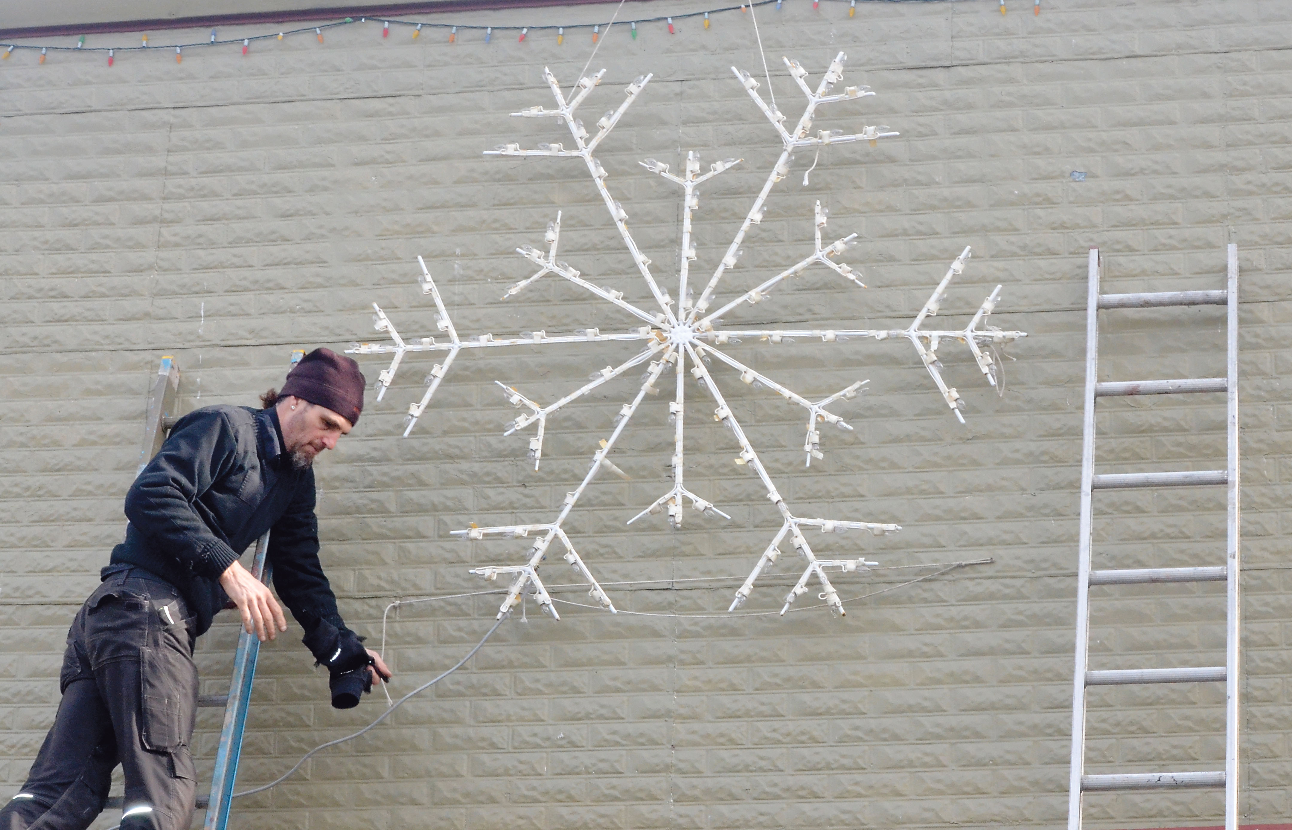 Dan Anderson installs a star on an uptown building in Port Townsend as the hanging of holiday lights commences this week. — Charlie Bermant/Peninsula Daily News