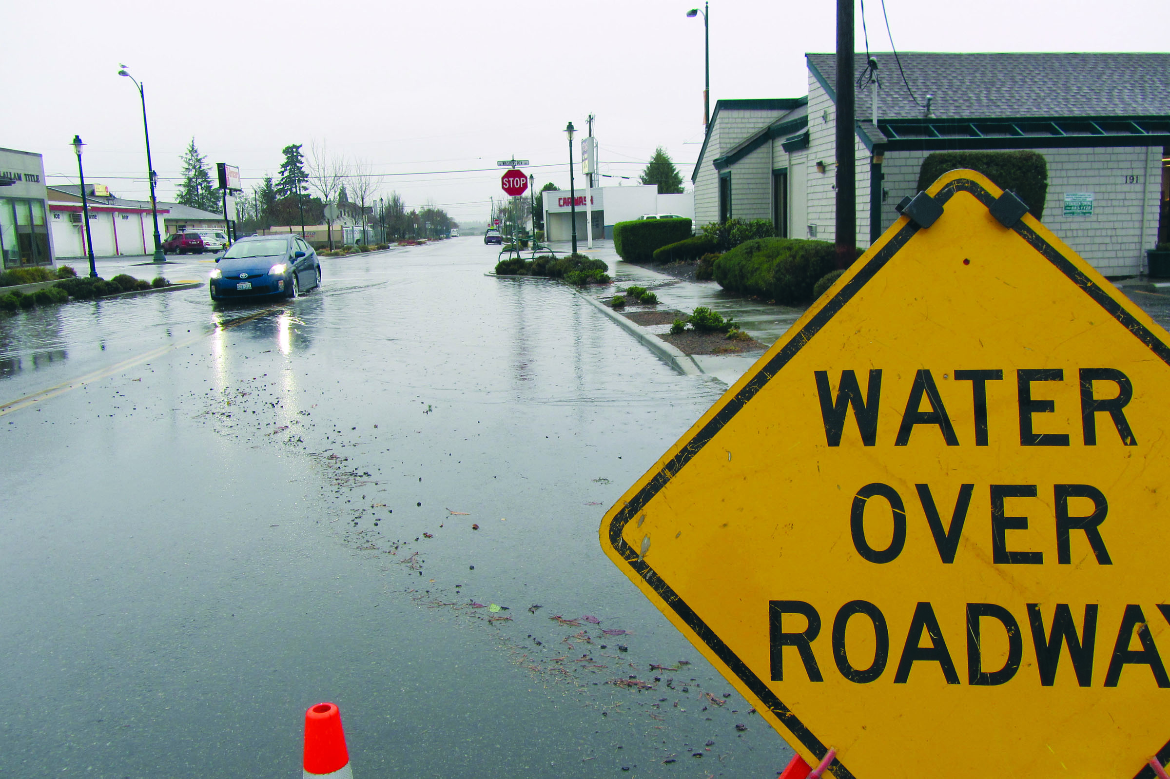 Water flows over curbs in Sequim during Monday’s heavy rains in a town that doesn’t have a storm drain system.  -- Photo by Jenifer Clark/Peninsula Daily News