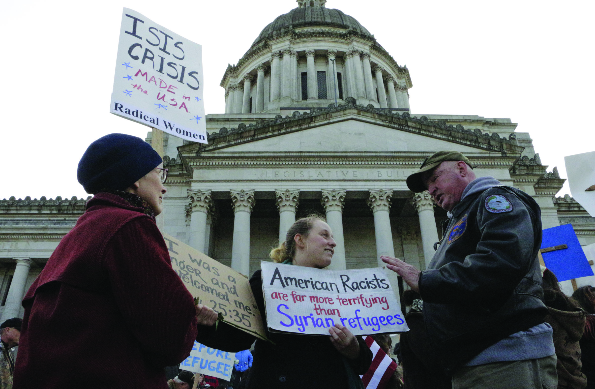 Protesters on opposing sides of the Syrian refugee resettlement issue rally in front of the state Capitol in Olympia on Friday. Gov. Jay Inslee has said the state will welcome refugees and has criticized other governors who have threatened to stop accepting them following last week’s terror attacks in Paris. — The Associated Press