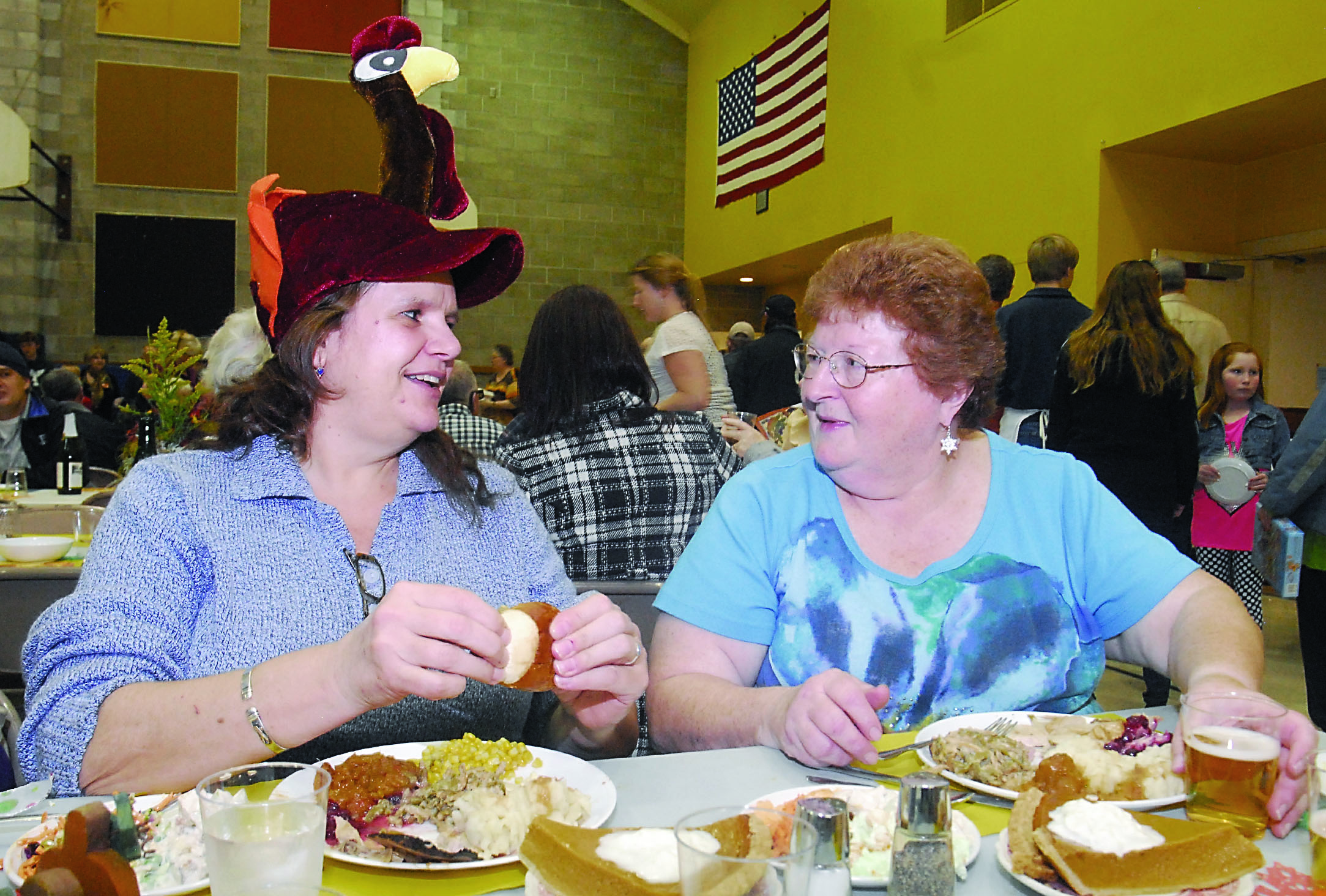 Chris Hurst of Port Angeles proves that not all the turkey was on the table Thursday during the community Thanksgiving dinner at Queen of Angels Church. At right is fellow diner Clair Kirkman.  —Photo by Keith Thorpe/Peninsula Daily News