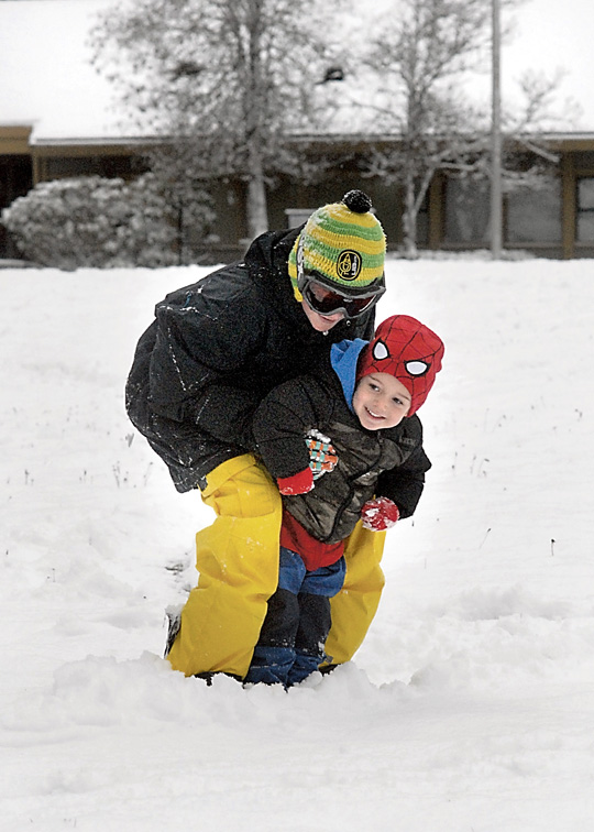 Three-year-old Kaston Beckett gets a snowboard ride from his cousin
