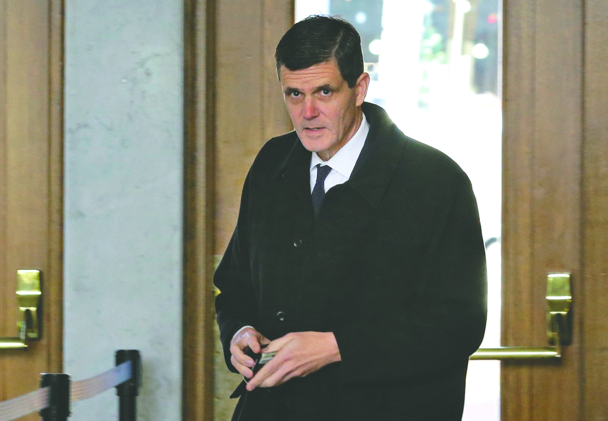 Washington state auditor Troy Kelley holds his wallet after showing his identification as he arrives for a federal court hearing Tuesday in Tacoma. — The Associated Press