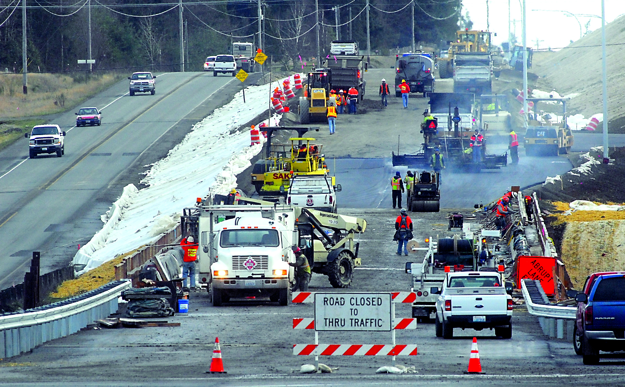 Construction crews work to pave the approach to the new U.S. Highway 101 bridge over McDonald Creek west of Sequim on Thursday as traffic continues to use the old highway. — Keith Thorpe/Peninsula Daily News