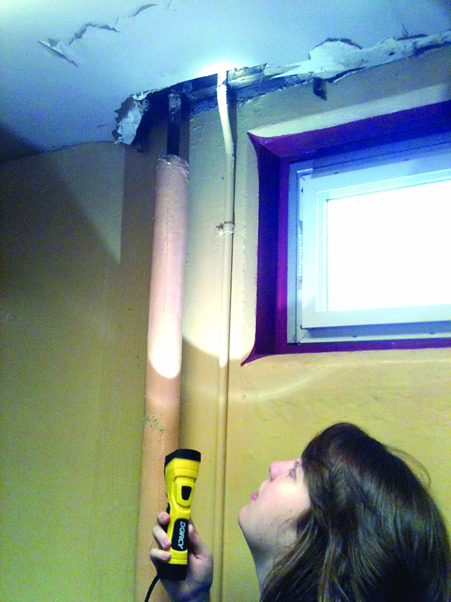 Pool employee Sarah Winslow shines some light on a portion of the ceiling in the women’s changing room at Mountain View Commons. The city of Port Townsend is looking for ways to pay for repairs of the building