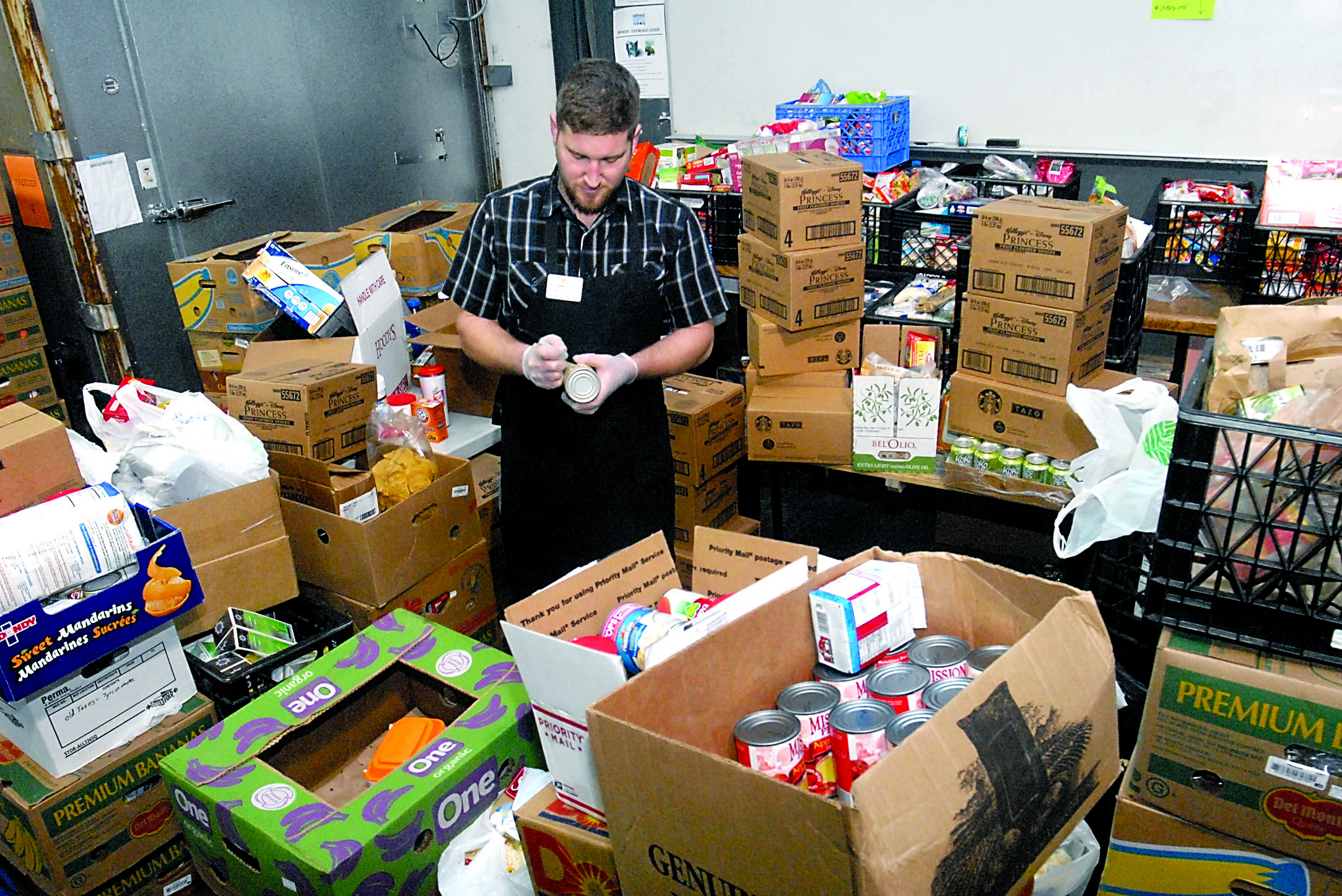 Port Angeles Food Bank warehouse manager Kevin Perry sorts through boxes of donated food