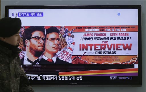 A South Korean army soldier walks near a TV screen showing an advertisement of Sony Picture’s “The Interview