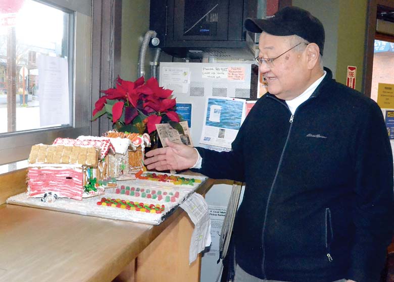 Aldrich's Market owner Milt Fukuda inspects the first entry in this year's Gingerbread House Contest