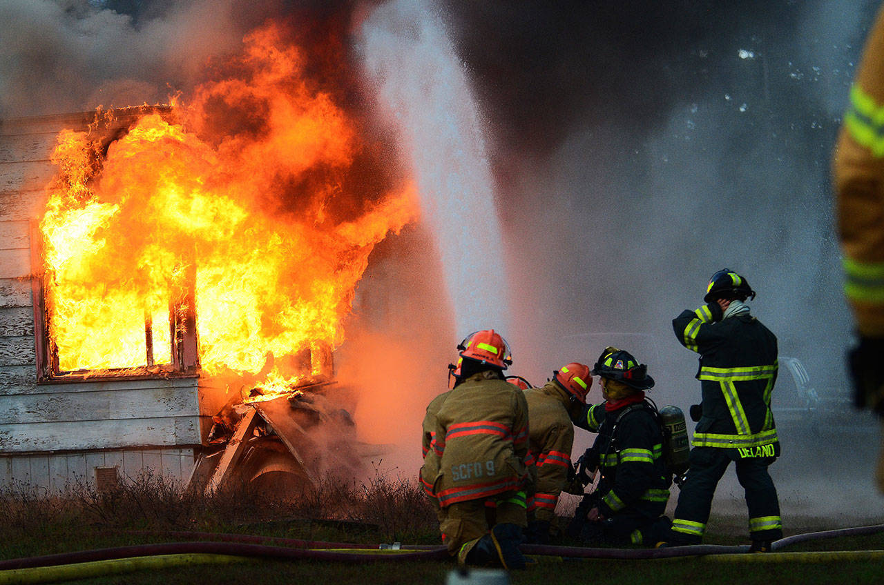 Firefighters coach youths in the Explorer Scouts program as they put water on a burning building during a training day in Port Angeles on Sunday. (Jesse Major/Peninsula Daily News)