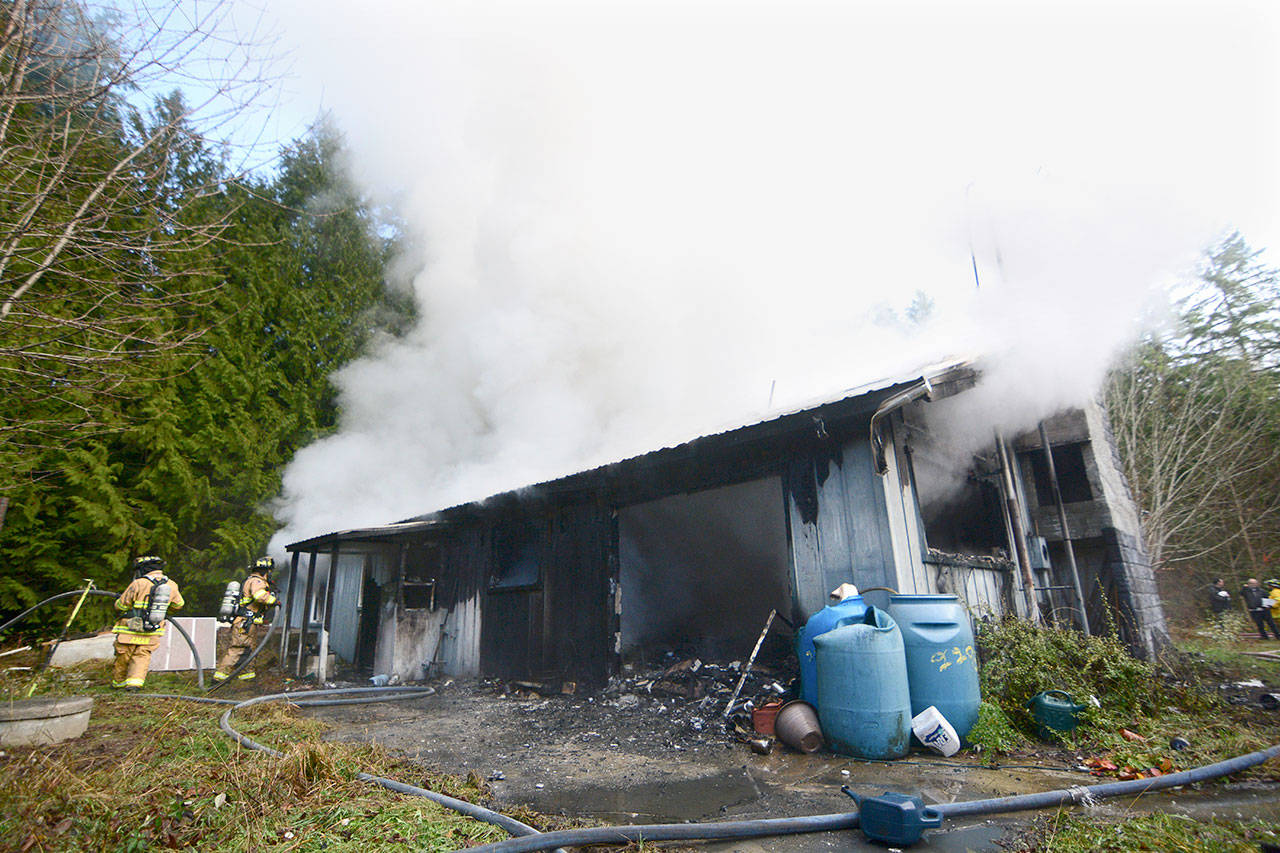 Firefighters continue to work as smoke and steam pour out of a Port Townsend-area home Thursday. The smoke could be seen from state Highway 20. (Jesse Major/Peninsula Daily News)