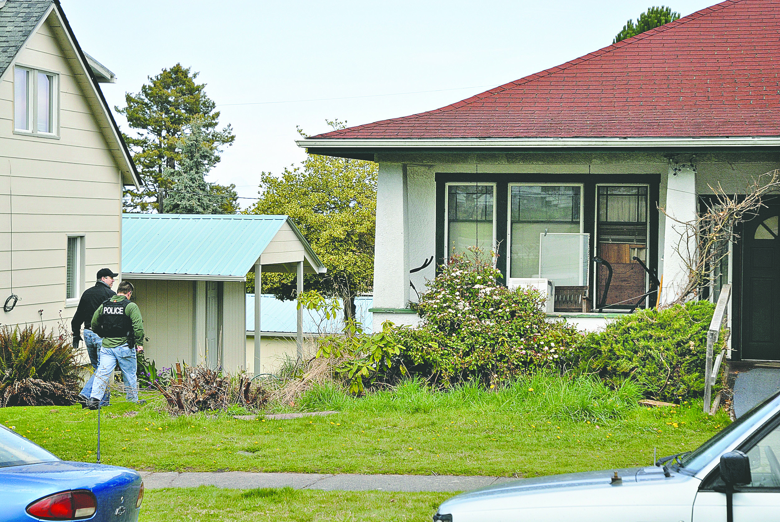Police walk around side of house