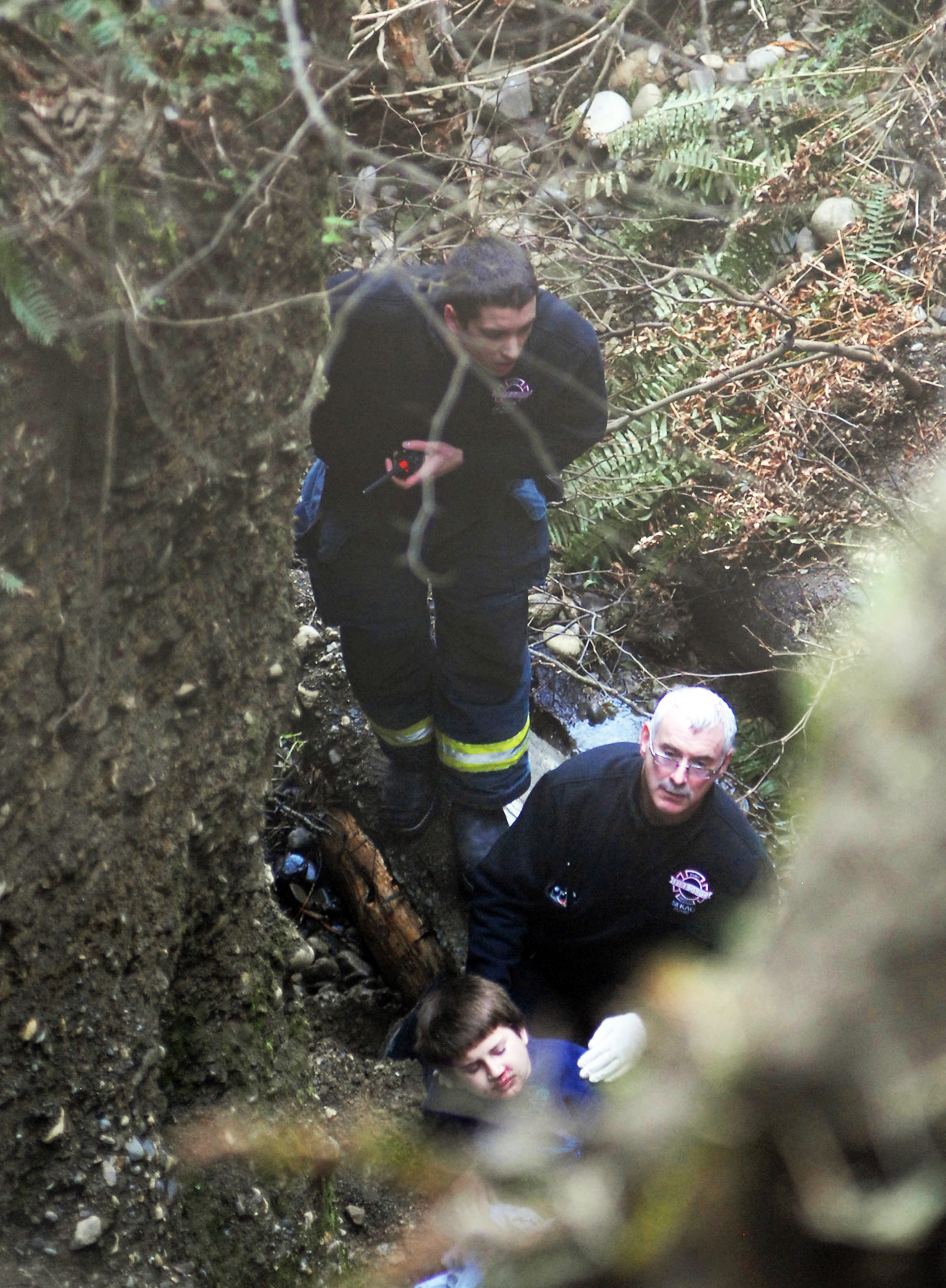 Rescue personnel stabilize the 9-year-old boy who fell over a bluff above the Nippon Paper Industries mill in west Port Angeles on Monday. Chris Tucker/Peninsula Daily News