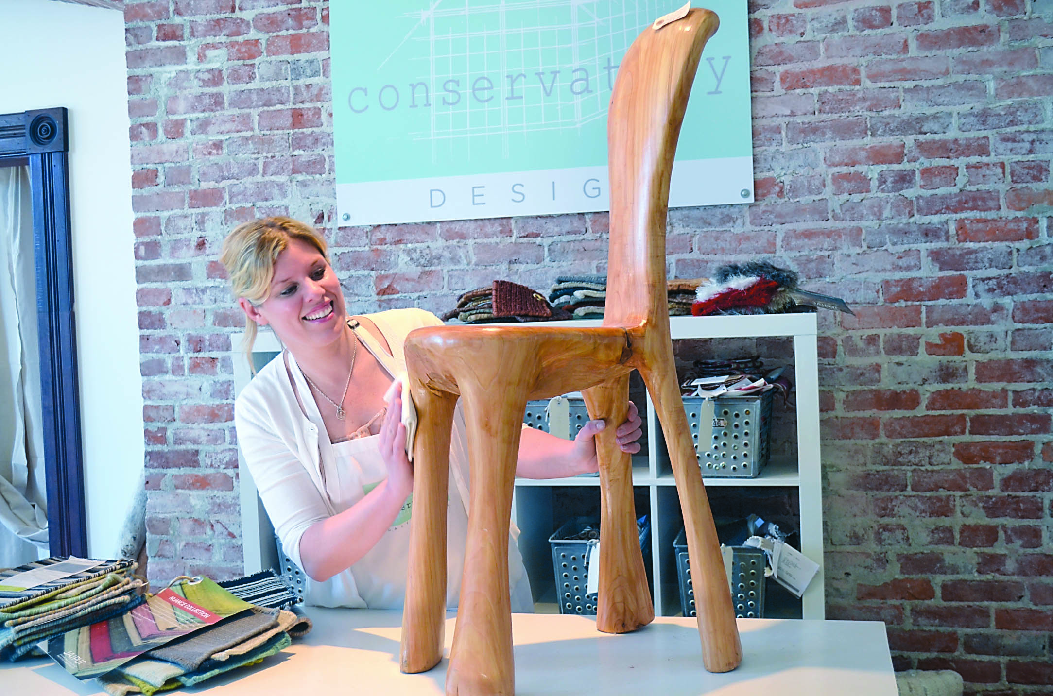 Heather Pollock polishes a one-of-a-kind chair made by River Casey before putting it on the display floor. Charlie Bermant/Peninsula Daily News