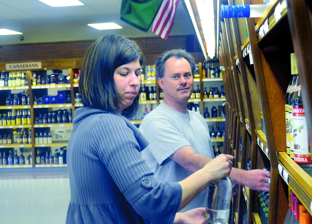 Melanie Newton and Tom Headley stock the shelves at the Port Townsend Liquor Store Tuesday. Charlie Bermant/Peninsula Daily News