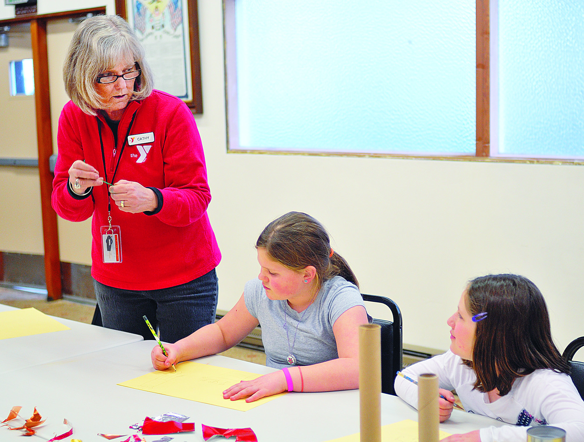 Longtime art instructor Cathy Haight helps Myra Walker and Sarah Howell with their mobiles during the Port Angeles YMCA’s After the Bell program.  -- Photo by Chris Tucker/Peninsula Profile