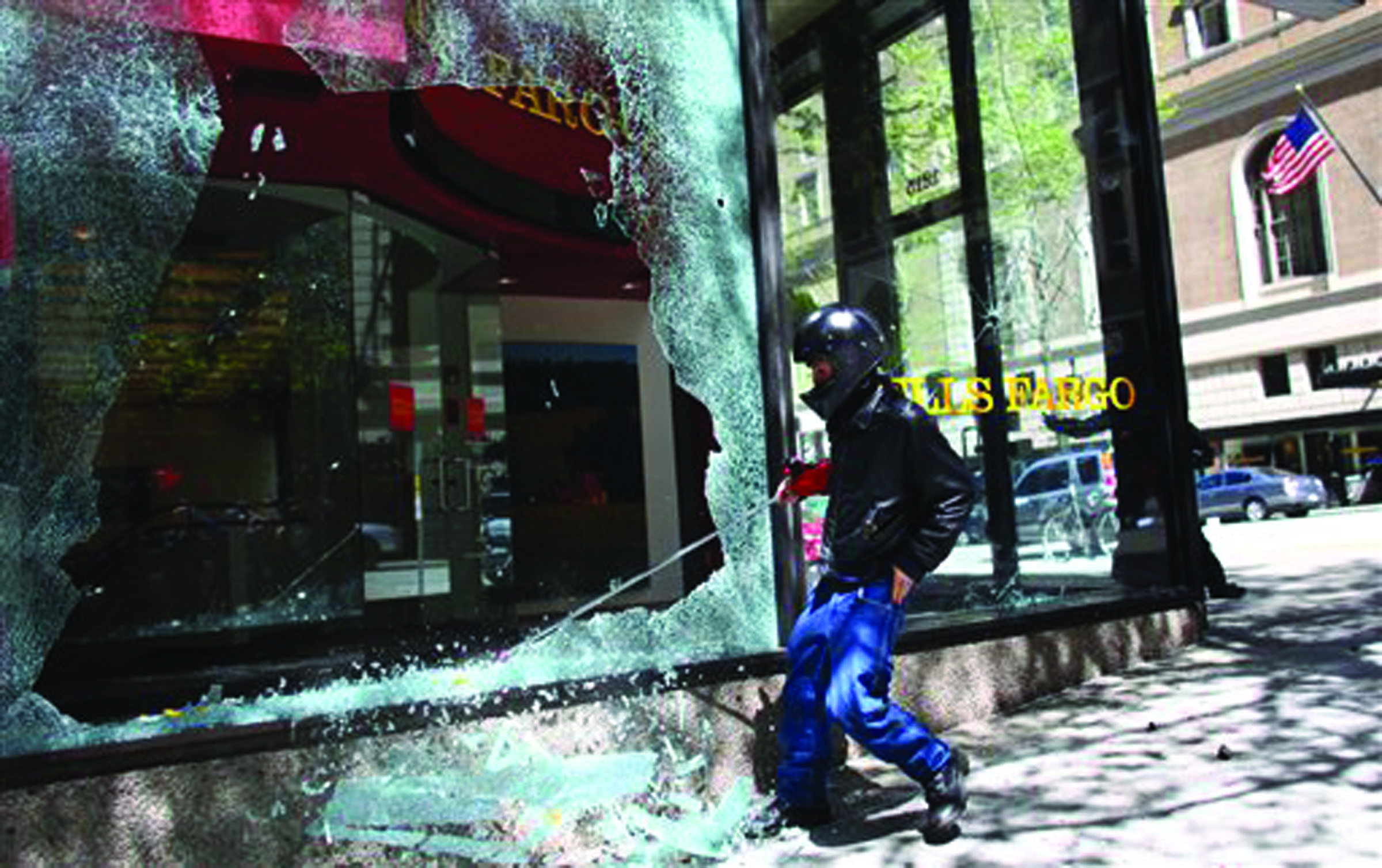 A protester smashes a window at a Wells Fargo branch during a May Day rally today in downtown Seattle. Mayor Mike McGinn says he’s making an emergency declaration allowing police to confiscate items that can be used as weapons following violent May Day protests that left storefronts and car windows shattered. -- Photo by Joshua Trujillo/Seattlepi.com via The Associated Press
