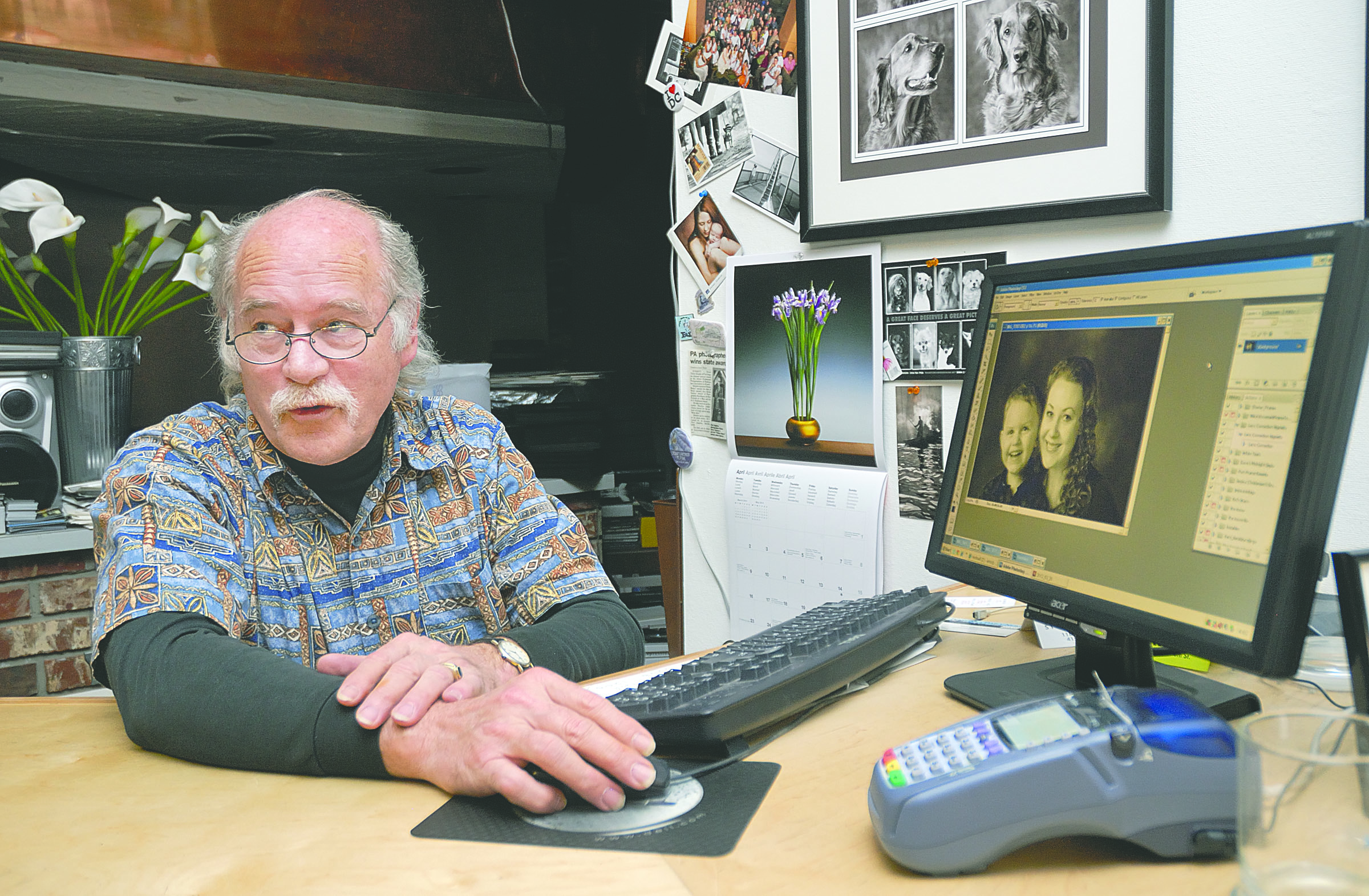 Ernst-Ulrich Schafer shows a photograph to one of his clients while working in his Port Angeles studio.  -- Photo by Chris Tucker/Peninsula Profile