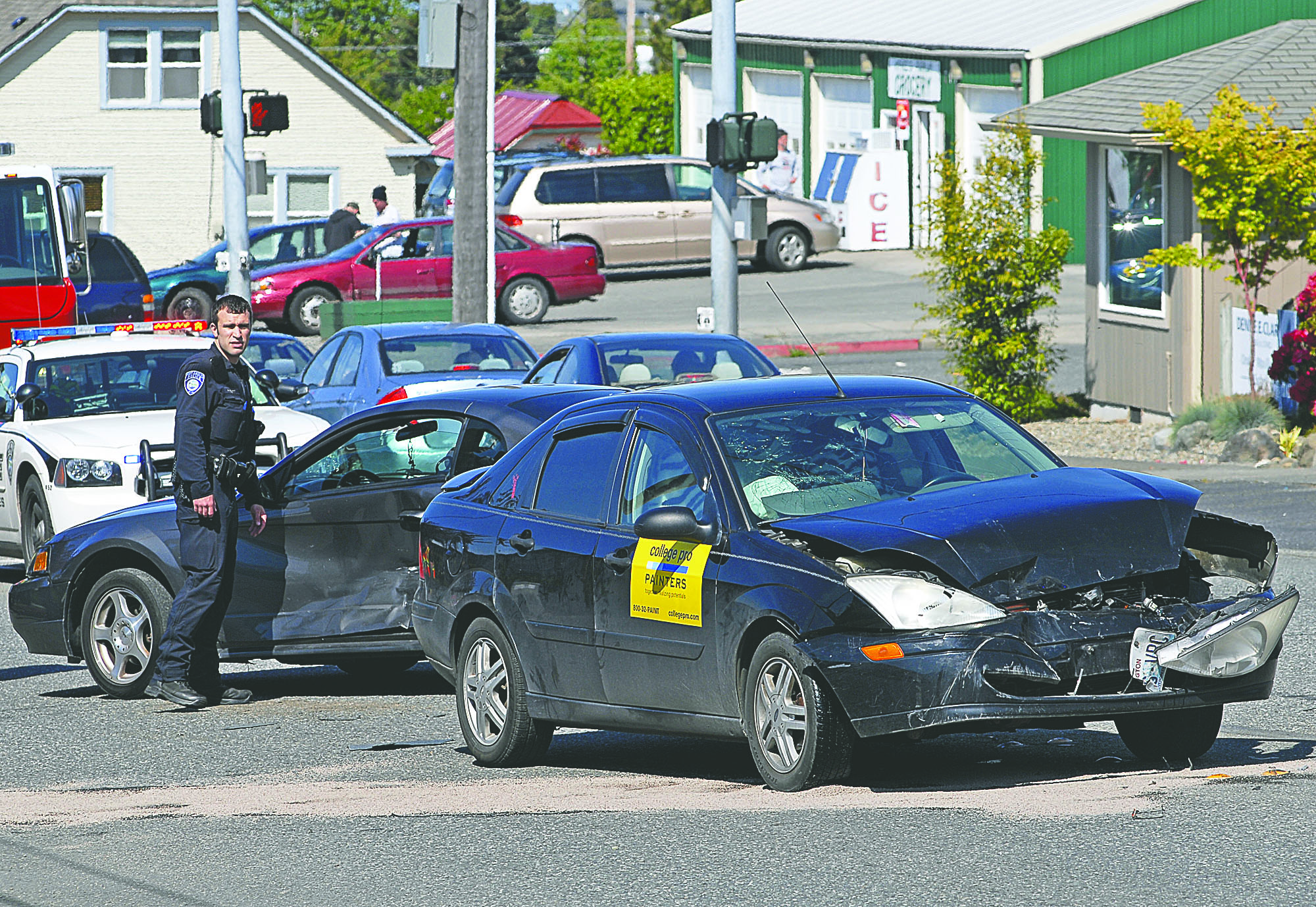Port Angeles Police Officer Andrew Heuett inspects damaged vehicles near the intersection of Eighth and Race streets Thursday. Chris Tucker/Peninsula Daily News