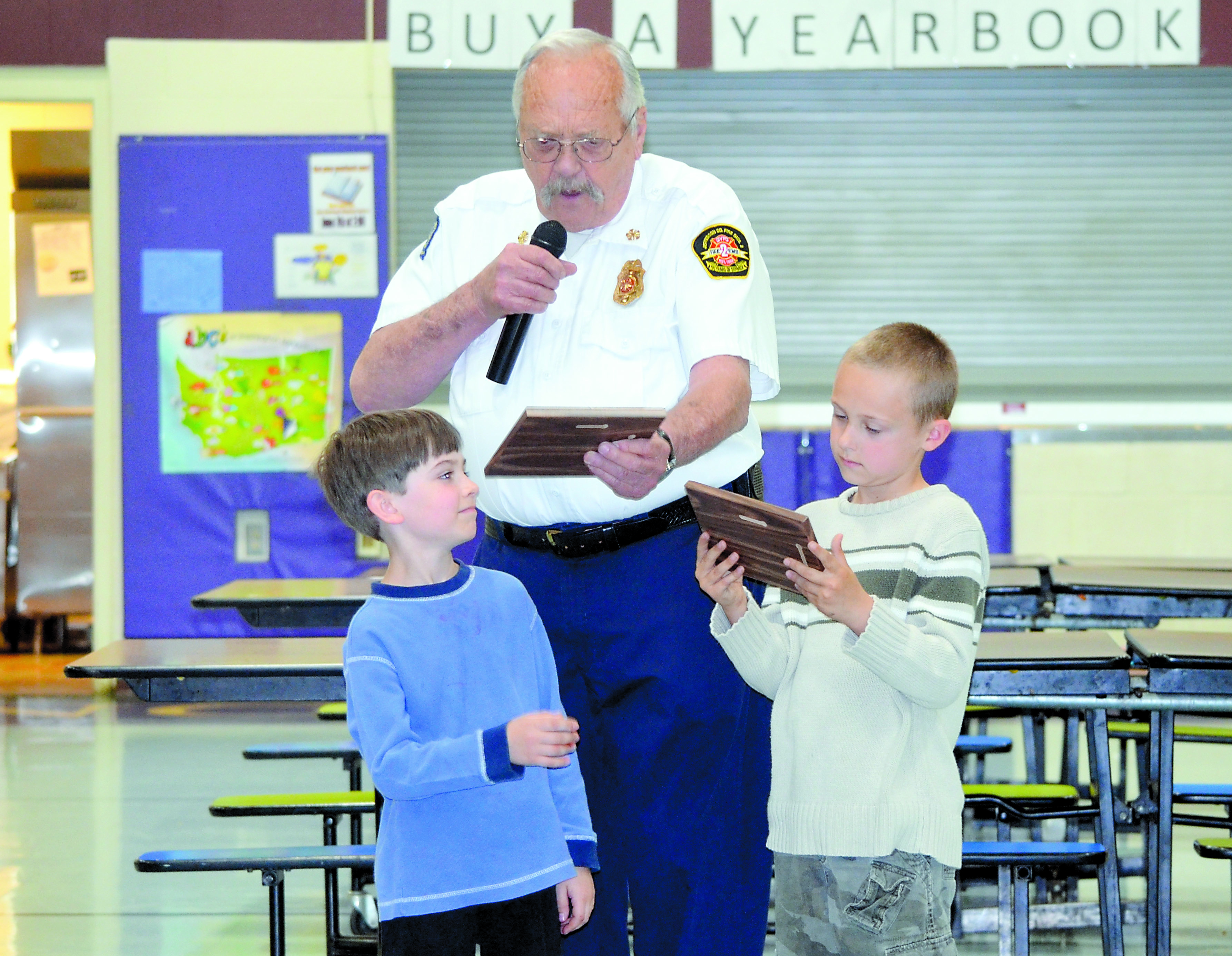 Quilcene Fire Chief Mo Moser awards plaques to Nathan Soderberg. left