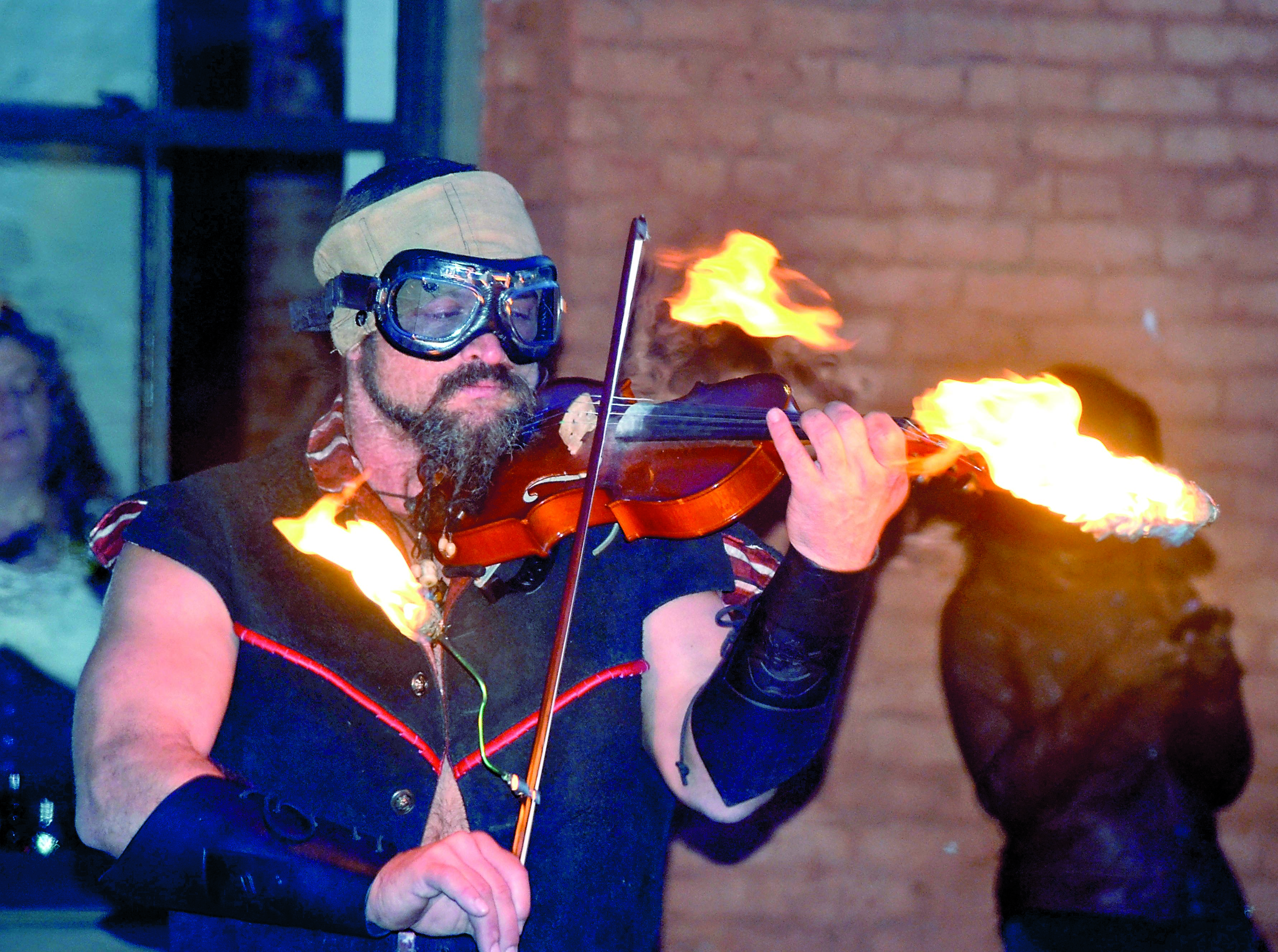 Robert Downing illustrates the spirit of steampunk with a combination of fire eating and fiddle playing.  -- Photo by Charlie Bermant/Peninsula Daily News