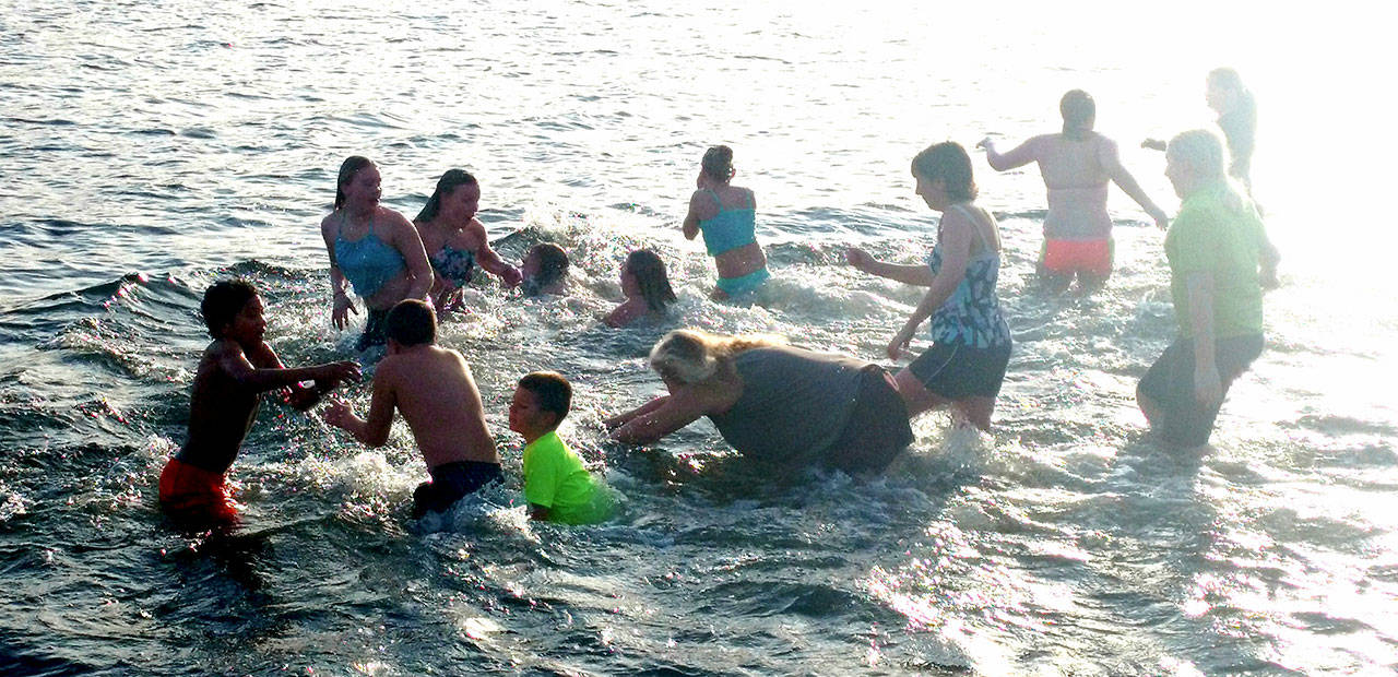 Participants take a quick dip in the 12th annual Polar Bear Plunge in Lake Pleasant. In the center, Elen Verzosa goes into the chilly water headfirst. (Zorina Barker/for Peninsula Daily News)