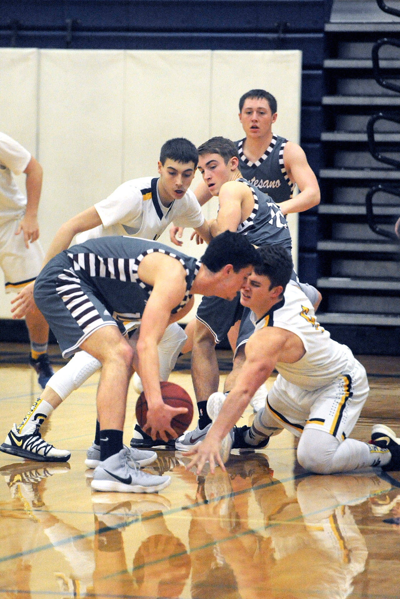 Lonnie Archibald/for Peninsula Daily News Forks’ Jake Jacoby (left) and Cole Baysinger (on floor) go for the steal against Montesano’s Trevor Ridgway. Forks defeated Montesano 49 to 46 in a thriller to take over first place in the Evergreen League.