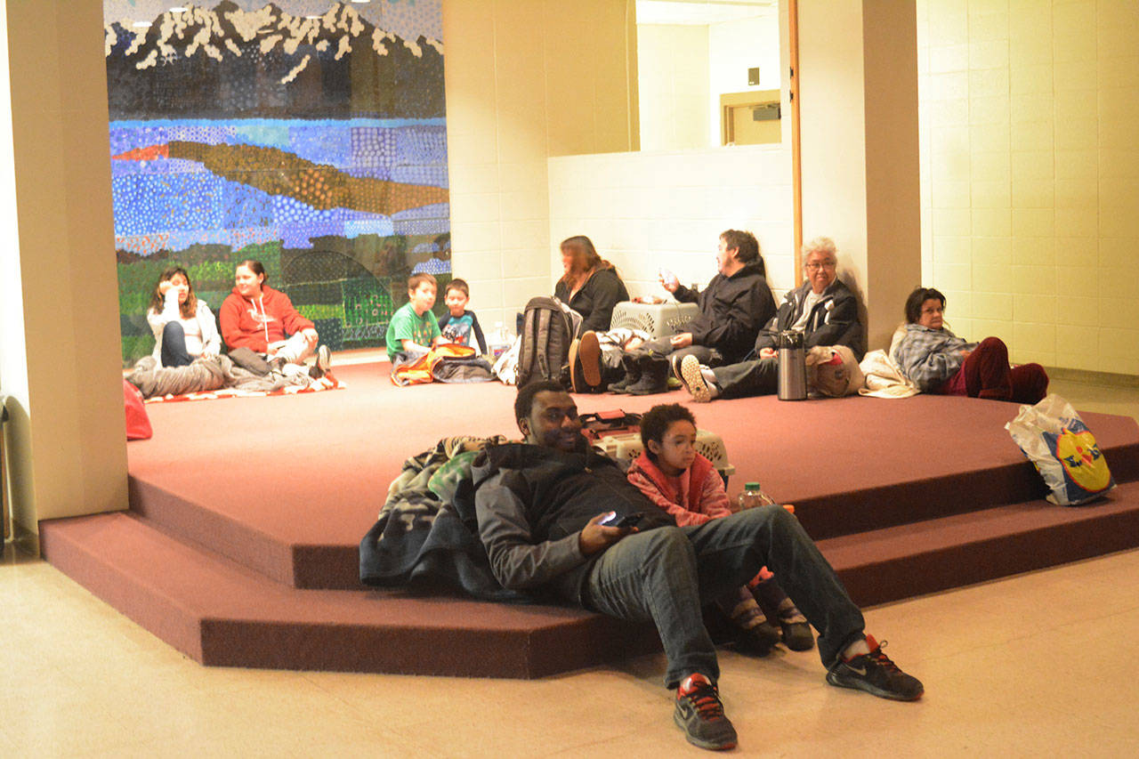 Abdulai Salam and his daughter, Mina, at about 2:30 a.m. Tuesday wait for the all-clear at Homer High School during a tsunami alert for Homer, Alaska. The city of Homer issued an evacuation order for low-lying areas shortly after an earthquake hit. (Michael Armstrong/Homer News via AP)