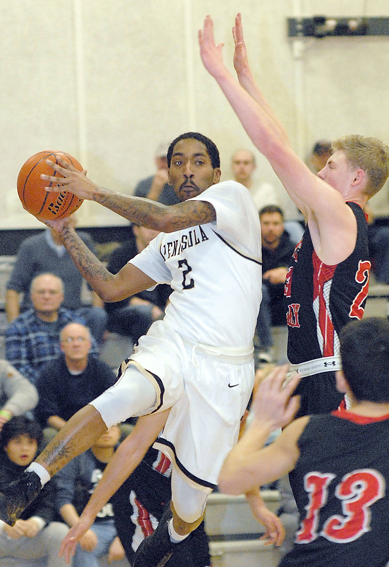 Peninsula’s Cameron Burton, left, takes to the air as Skagit Valley’s Nate Maudlin and Chris Walcott, lower right, defend the lane during the first half of the Pirates’ 82-80 loss. Keith Thorpe/Peninsula Daily News