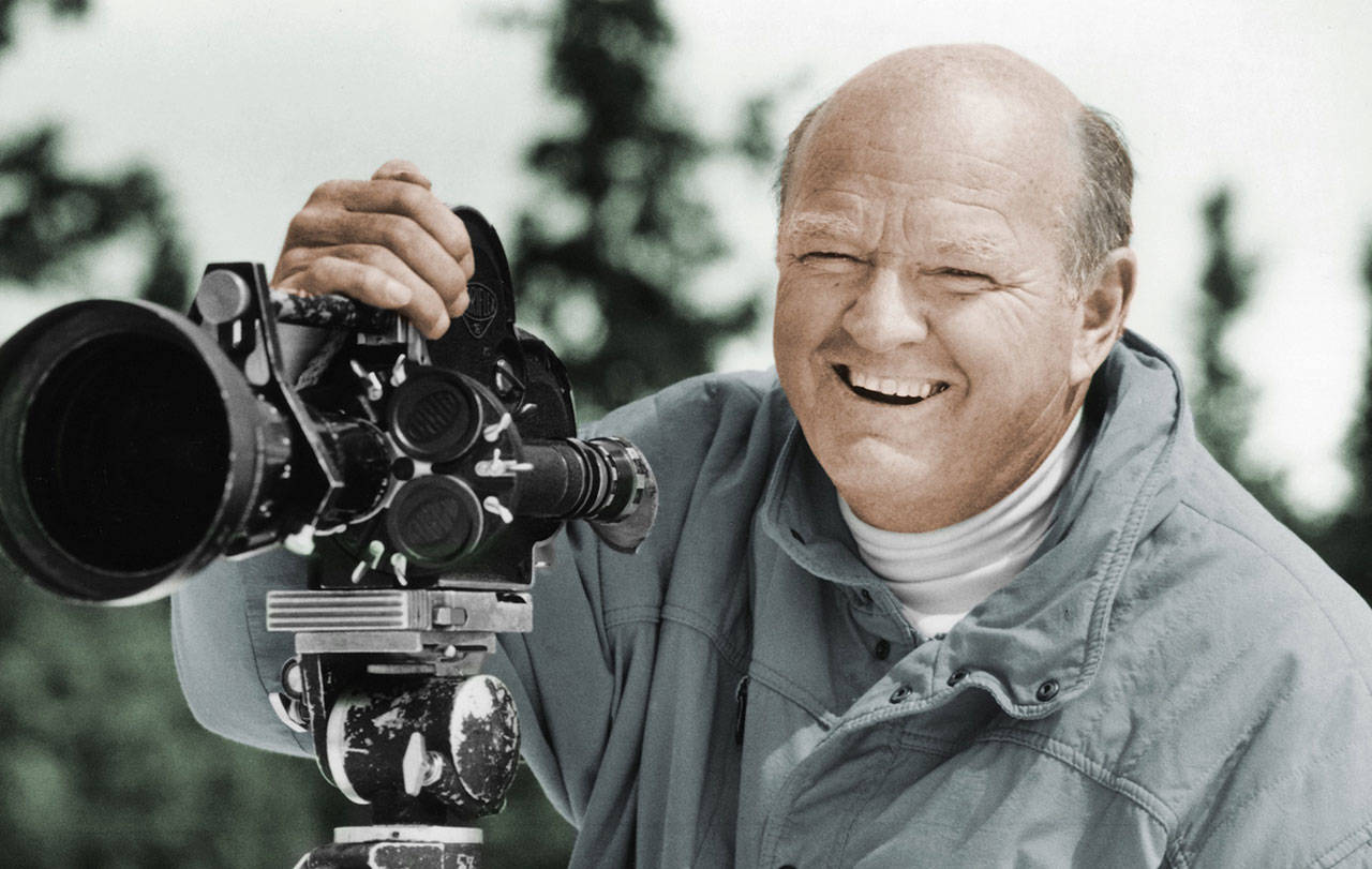 In this undated photo provided by the Warren Miller Co., Warren Miller is shown posing for a photo with a film camera. (Warren Miller Co./via The Associated Press)