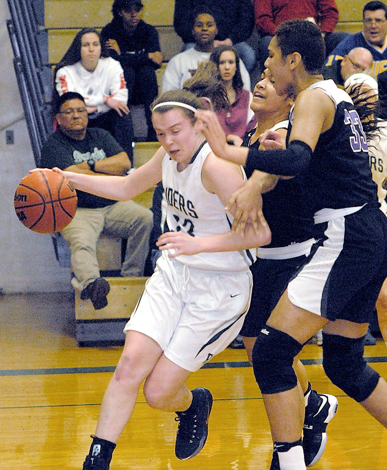 Port Angeles’ Jaida Wood, left drives along the baseline past Foster defenders Moeshana Maiava and Emolani Morris, right, in the second quarter of Friday night’s playoff game at Port Angeles High School. Keith Thorpe/Peninsula Daily News