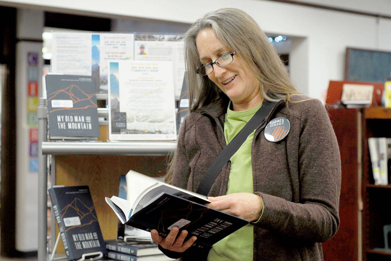 Cheryl Wallace of Port Townsend peruses a copy of Leif Whittaker’s “My Old Man and the Mountain,” this year’s Port Townsend Community Read selection, from the library display. Wallace said she heard Whittaker make a presentation in the past and believes the book will be as interesting and compelling as his talk. (Jeannie McMacken/for Peninsula Daily News)