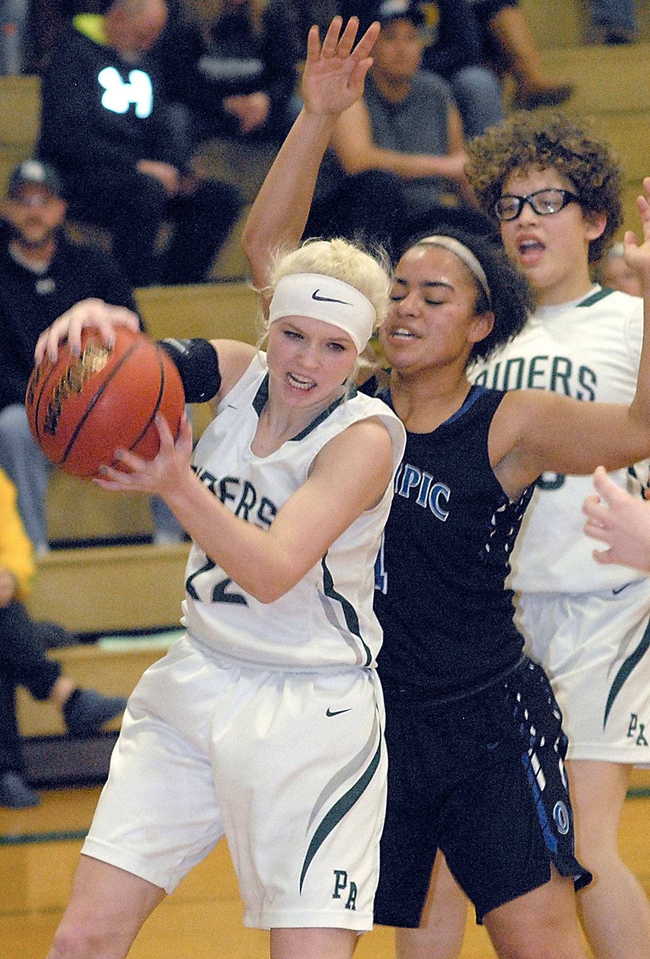 Port Angeles’ Natalie Steinman, left, grabs a rebound in front of Olympic’s Kiki Mitchell on Feb. 1, in Port Angeles. In the background is Steinman’s teammate, Madison Cooke. (Keith Thorpe /Peninsula Daily News)