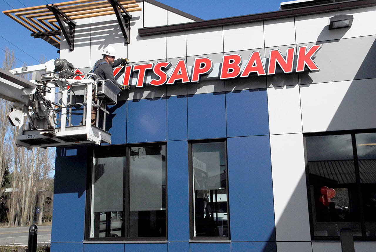 Brian Walters from Hanson Signs in Bremerton puts the finishing touches on the newly remodeled Kitsap Bank branch in Port Townsend. The building, which opened Monday, features green design, solar roof panels and recycled building products. (Jeannie McMacken/Peninsula Daily News)