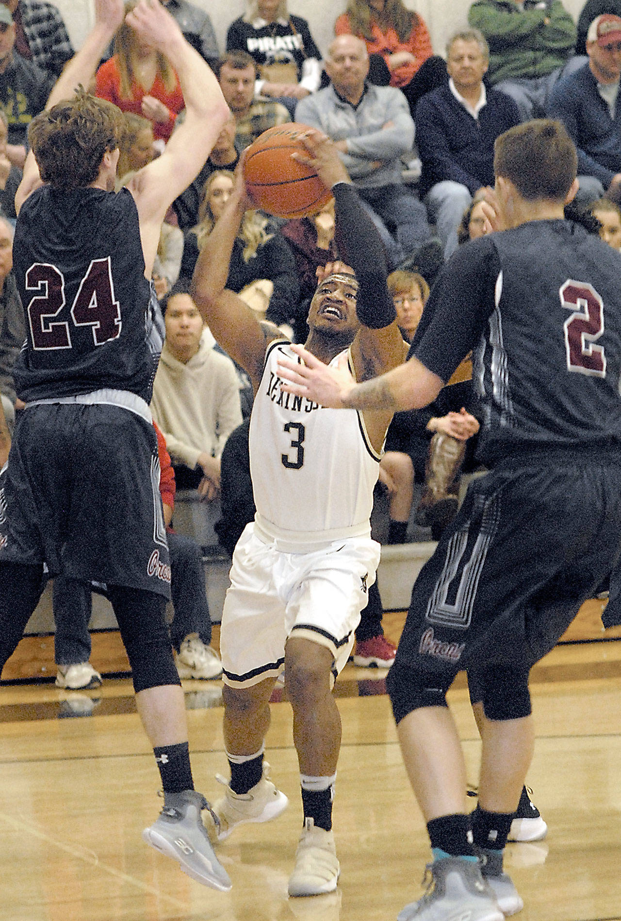 Keith Thorpe/Peninsula Daily News Peninsula’s Colby Jackson, center, goes for the bucket while sandwiched between Whatcom’s Tanner Clark, left, and Tevin Bayne on Wednesday in Port Angeles.
