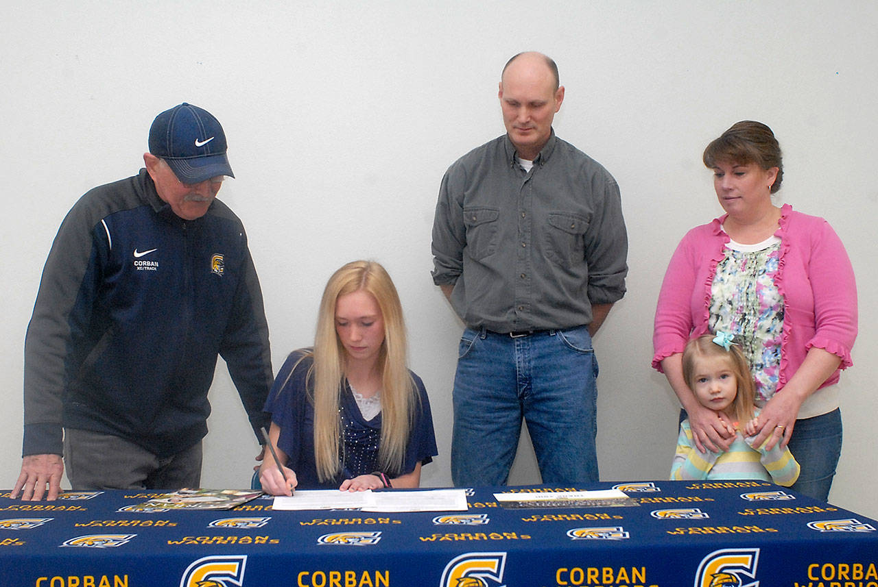 Port Angeles multi-sport athlete Gracie Long, seated, signs a letter of intent to attend Corban University in Salem, Ore., while surrounded by, from left, Corban track and cross-country coach Norm Berney, her parents, Kenton and Alyssa Long, and sister, Tessa Long, 4, on Wednesday at Port Angeles High School. Keith Thorpe/Peninsula Daily News