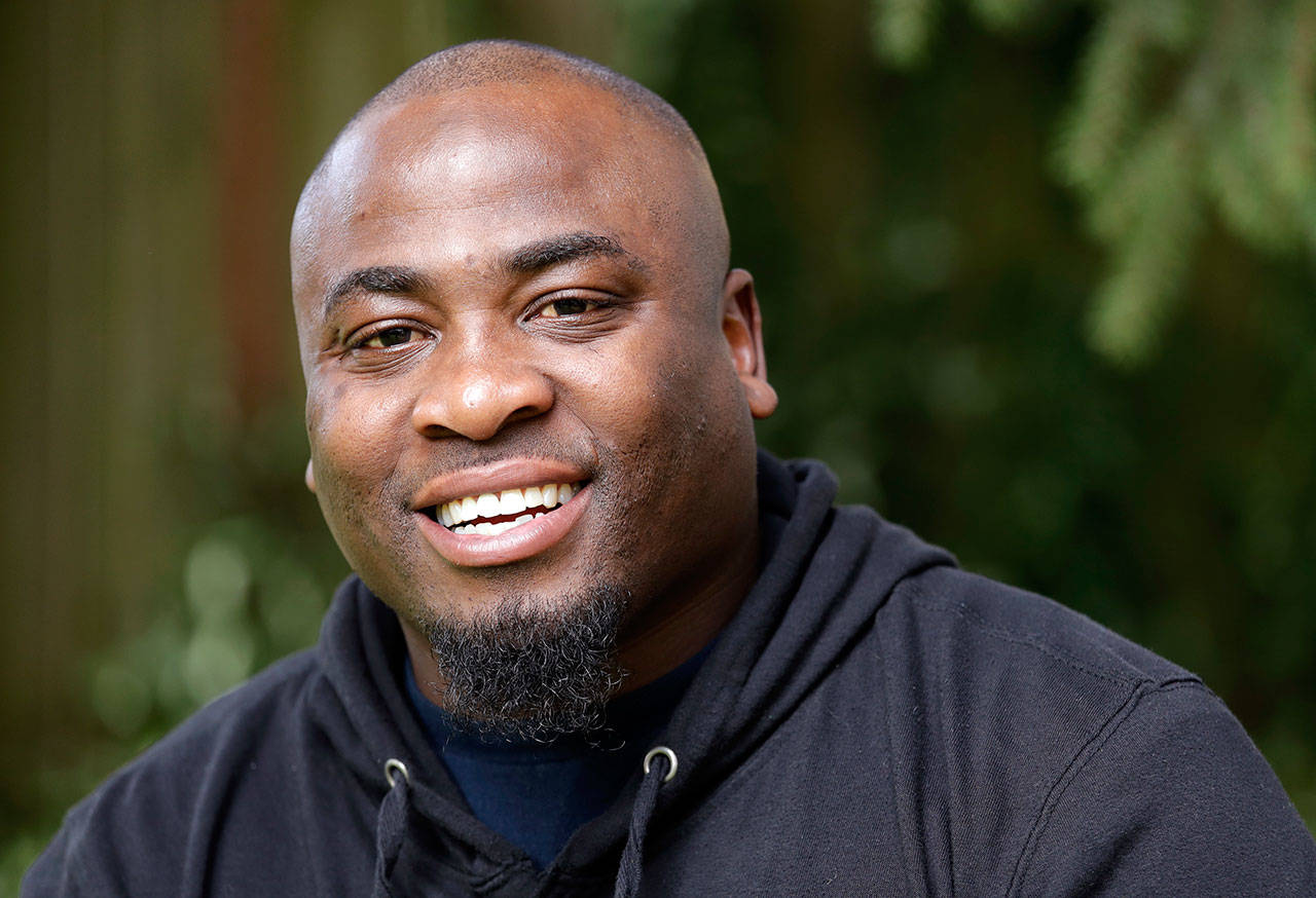 Orlando Wright smiles as he poses for a photo at his home in Kent. Wright, who was released from a Washington state prison a few months early due to a software glitch, is suing the Department of Corrections, saying his re-arrest three years later to serve the remaining time was illegal and upended the life he had painstakingly rebuilt. (Elaine Thompson/The Associated Press)