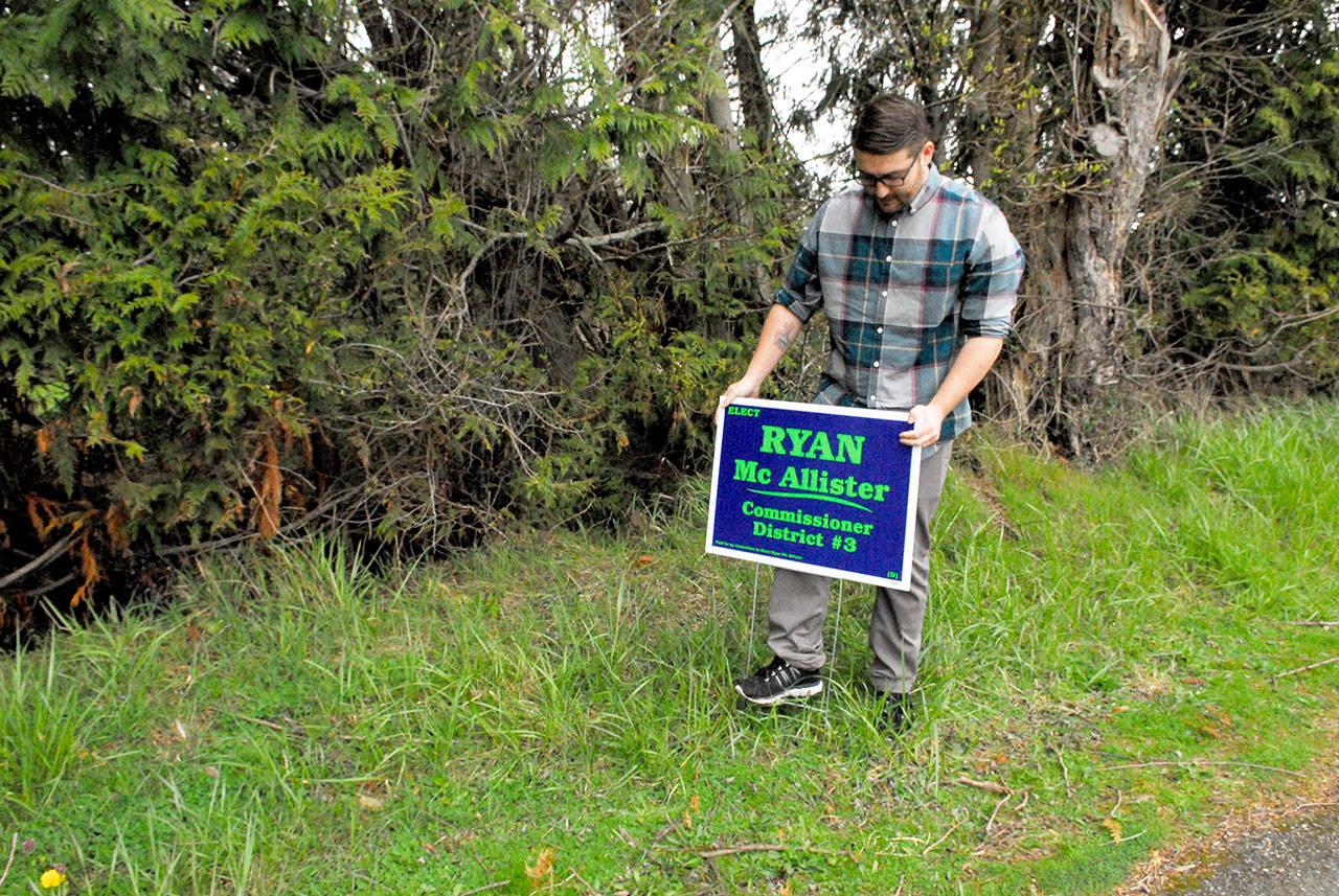 Candidate Ryan McAllister replaces one of his campaign signs that was stolen from a right of way in Brinnon. (Jeannie McMacken/Peninsula Daily News)