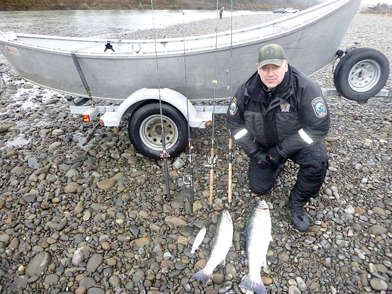 Washington Department of Fish and Wildlife Police Officer Bryan Davidson displays two wild steelhead and an undersized cutthroat trout along with the rods used to poach the fish after a January incident on the Quillayute River near Forks. (Washington Department of Fish and Wildlife Police)
