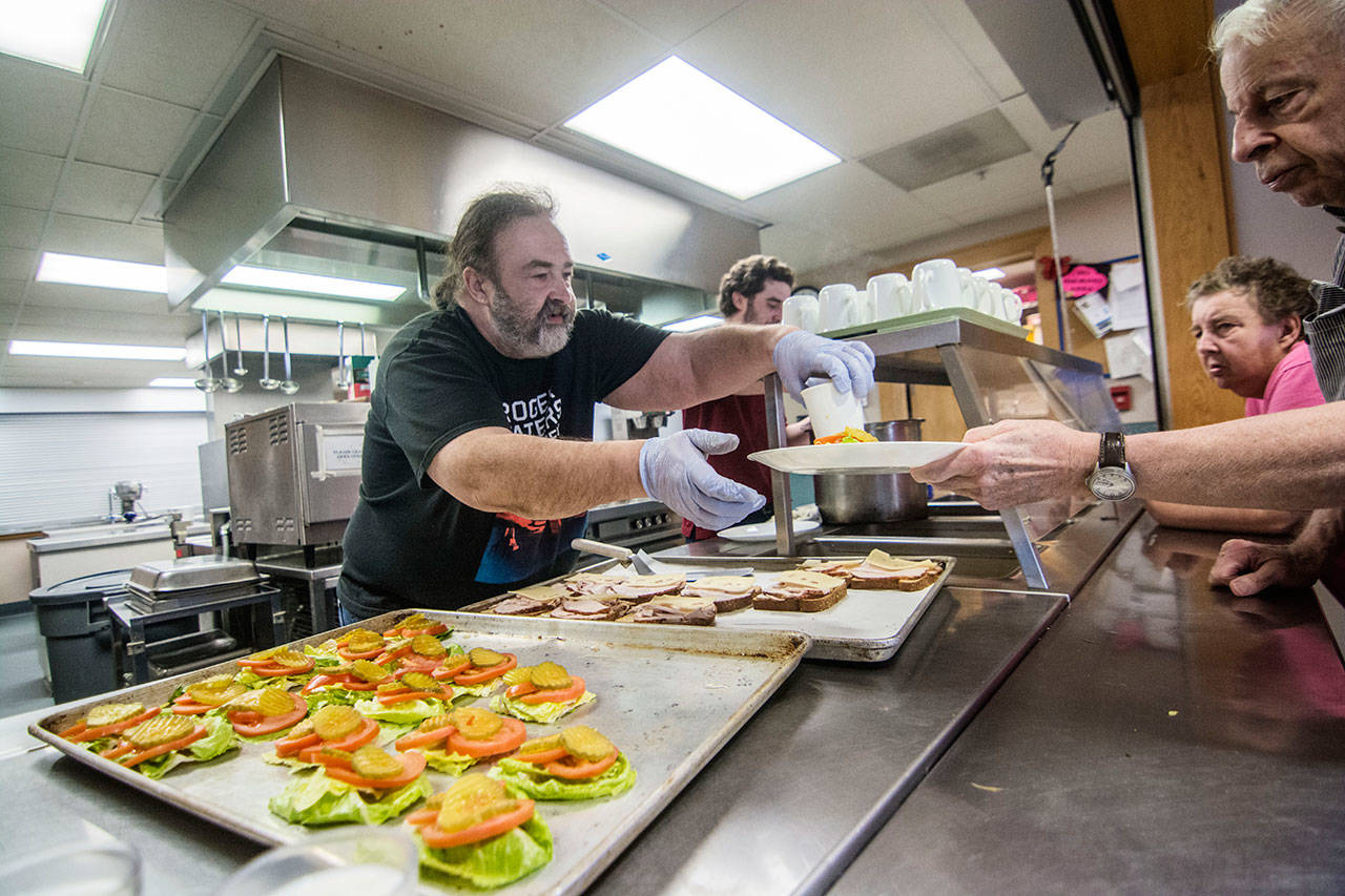 Kitchen aid Floyd Watry serves up vegetable soup and turkey and cheese sandwiches during Olympic Community Action Program’s congregate meal at the Port Angeles Senior Center. (Jesse Major/Peninsula Daily News)