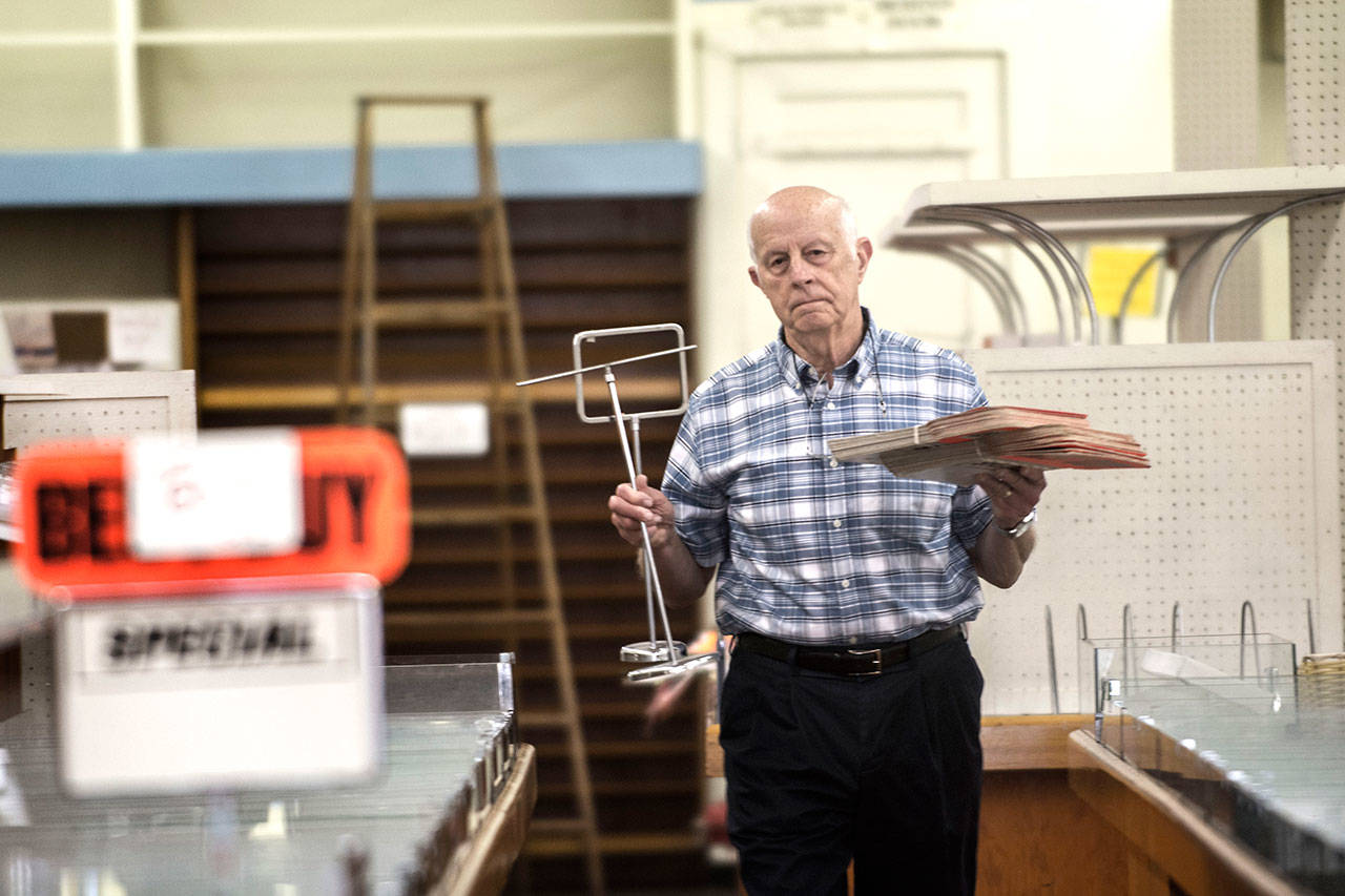 Rudy Hiener, whose daughter owns Bay Variety, walks past empty shelves as he carries items to the front of the store Monday. (Jesse Major/Peninsula Daily News)