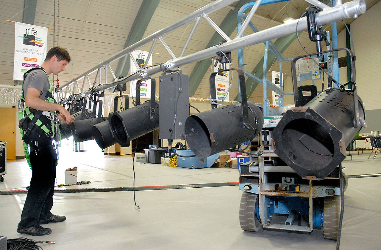 Luke Kehrwald of Seattle-based Performance Sound configures a rack of suspended spotlights Thursday in the Vern Burton Community Center in preparation for this weekend’s Juan de Fuca Festival of the Arts in Port Angeles. (Keith Thorpe/Peninsula Daily News)