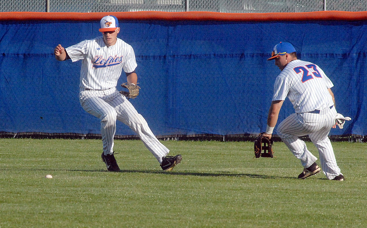 Keith Thorpe/Peninsula Daily News Lefties center fielder Dalton Harum, left, and right fielder Austin Earl chase after a ball hit by the Victoria Harbourcats during the Lefties’ home opener on Thursday at Port Angeles Civic Field.