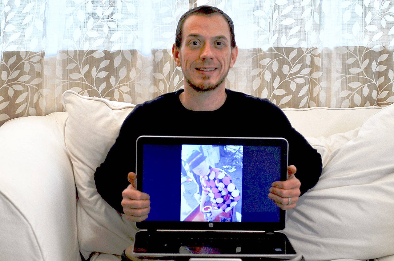 Pastor Tony Brown of Trinity United Methodist Church in Port Townsend holds an image of Walter Maphalala, a young man with albinism living in Swaziland, in February. (Jeannie McMacken/Peninsula Daily News)