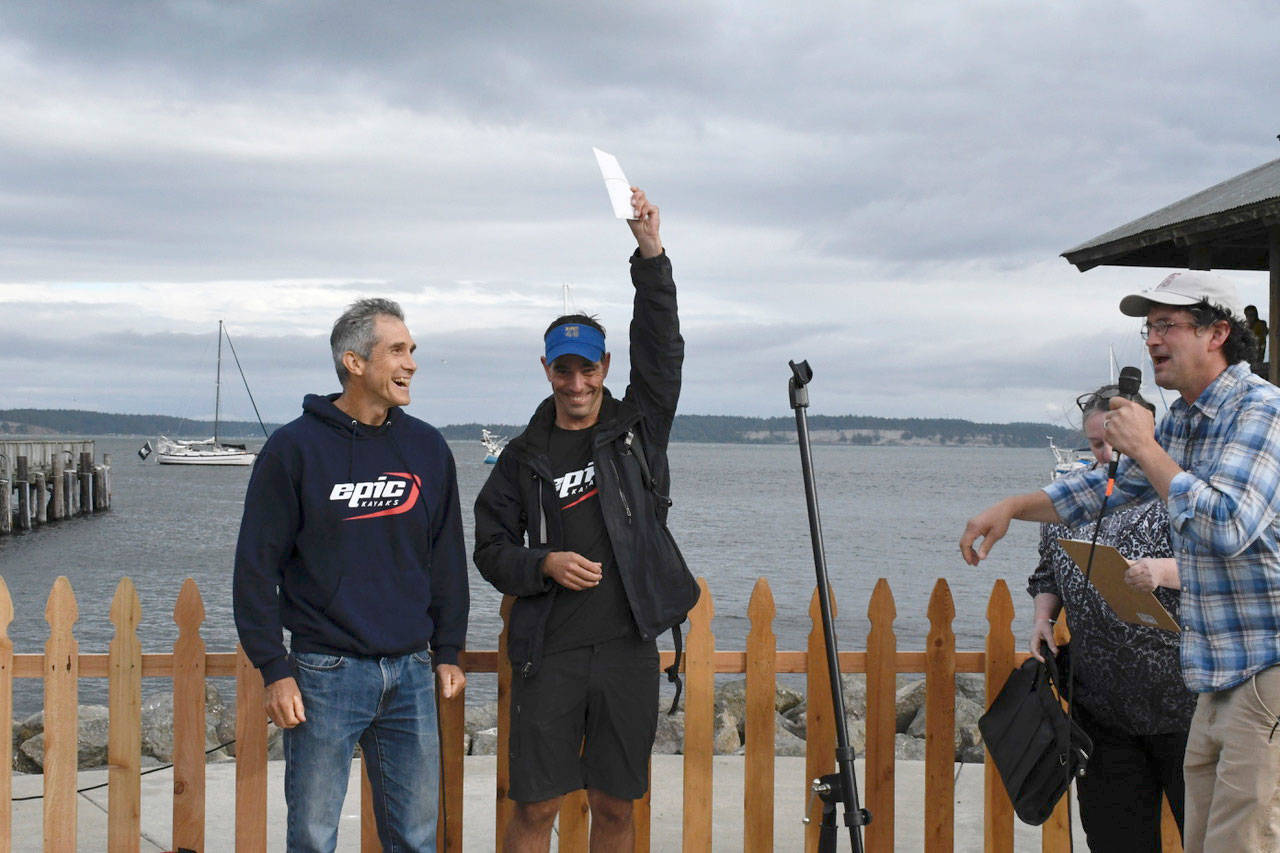 Greg Barton, left, and Ken Olney received a $11,700 check Wednesday for their first-place finish in the inaugural Seventy48 human-powered boat race. Race Boss Daniel Evans, right, said the team was strong from the start and set a blistering pace. Of the 117 teams who entered the event, six left the race with soreness, weariness and a broken oar. (Jeannie McMacken/Peninsula Daily News)