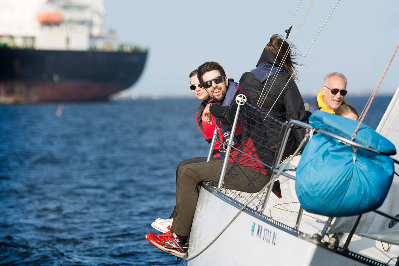 Crew members of the Wild Thing hang over the side of their boat during the Port Angeles Yacht Club’s “beer can” races in the Port Angeles Harbor on Friday. (Jesse Major/Peninsula Daily News)