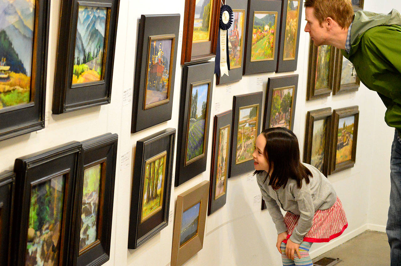 Audrey Sunwoo Dalton, 5, and her father, Toby Dalton, admire some of the award winners in the Paint the Peninsula display at the Port Angeles Fine Arts Center on Saturday. Toby, who grew up in Port Angeles, lives in Arlington, Va.; he brought Audrey to visit her grandmother Anne Dalton, an organizer of Paint the Peninsula. (Diane Urbani de la Paz/for Peninsula Daily News)