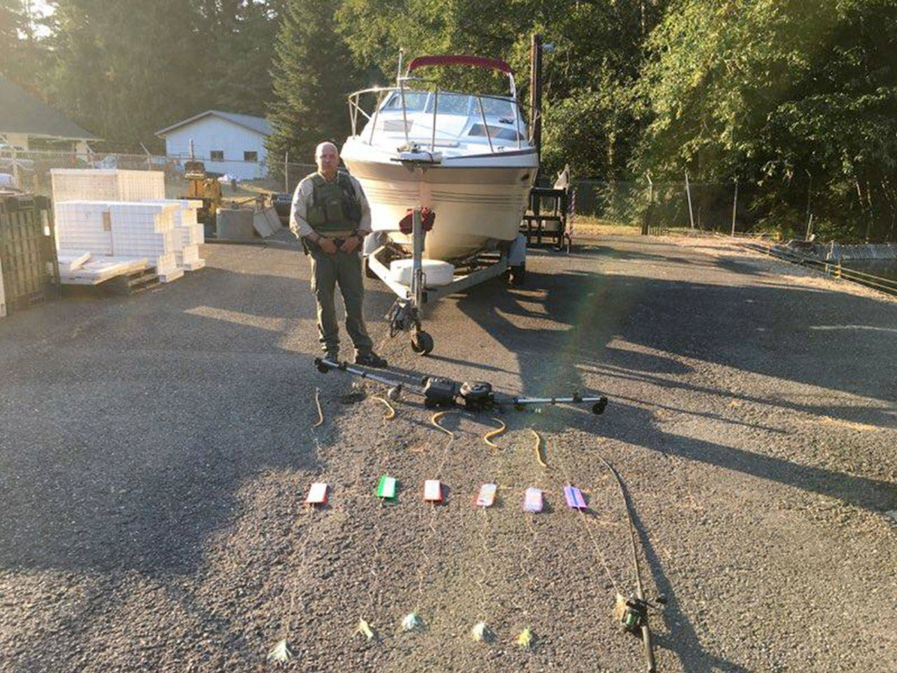 An officer stands behind six fishing lines allegedly used to catch salmon near Sekiu. (Washington Department of Fish and Wildlife)