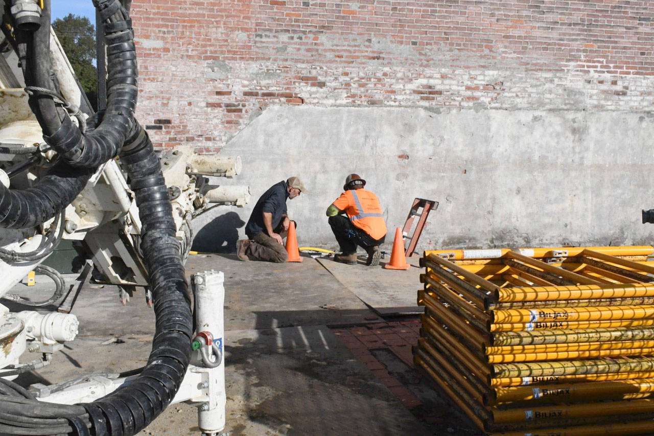 Site manager Scott Nollette, left, and Condon Johnson, both of Hodlick Construction, inspect some below grade stabilization work being done to pier pilings under what was the old Surf Building on Taylor Street in Port Townsend. The site is being developed as Hastings Landing, a multi-story boutique hotel and passenger terminal next to Union Wharf and adjacent to the Hastings Building. (Jeannie McMacken/Peninsula Daily News)